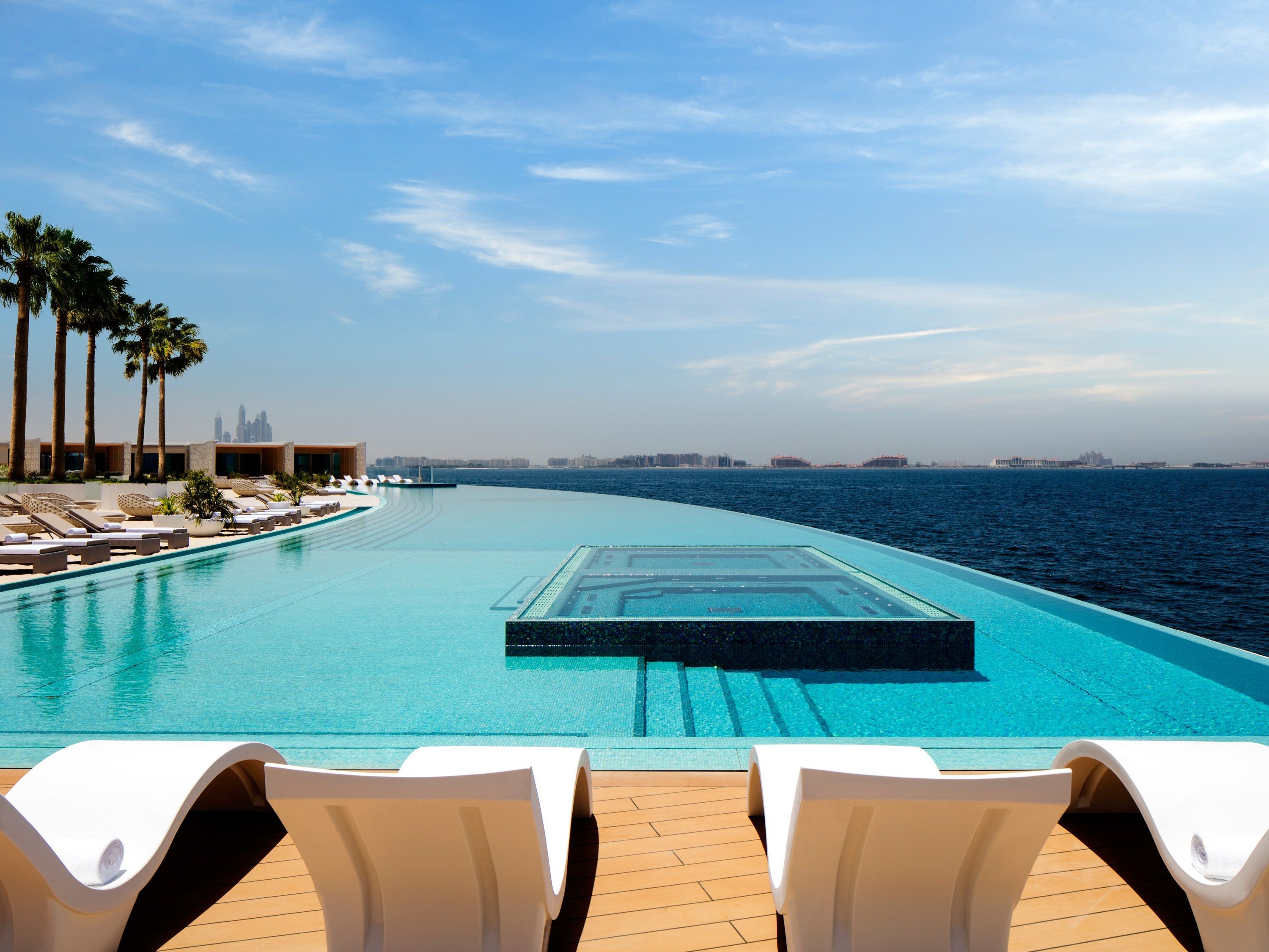 A pool with lounge chairs and palm trees - Swimming pool