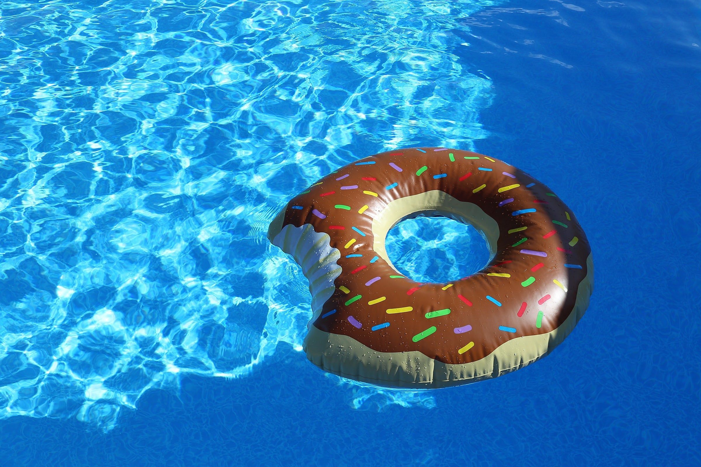 A donut shaped float in the middle of an open pool - Swimming pool