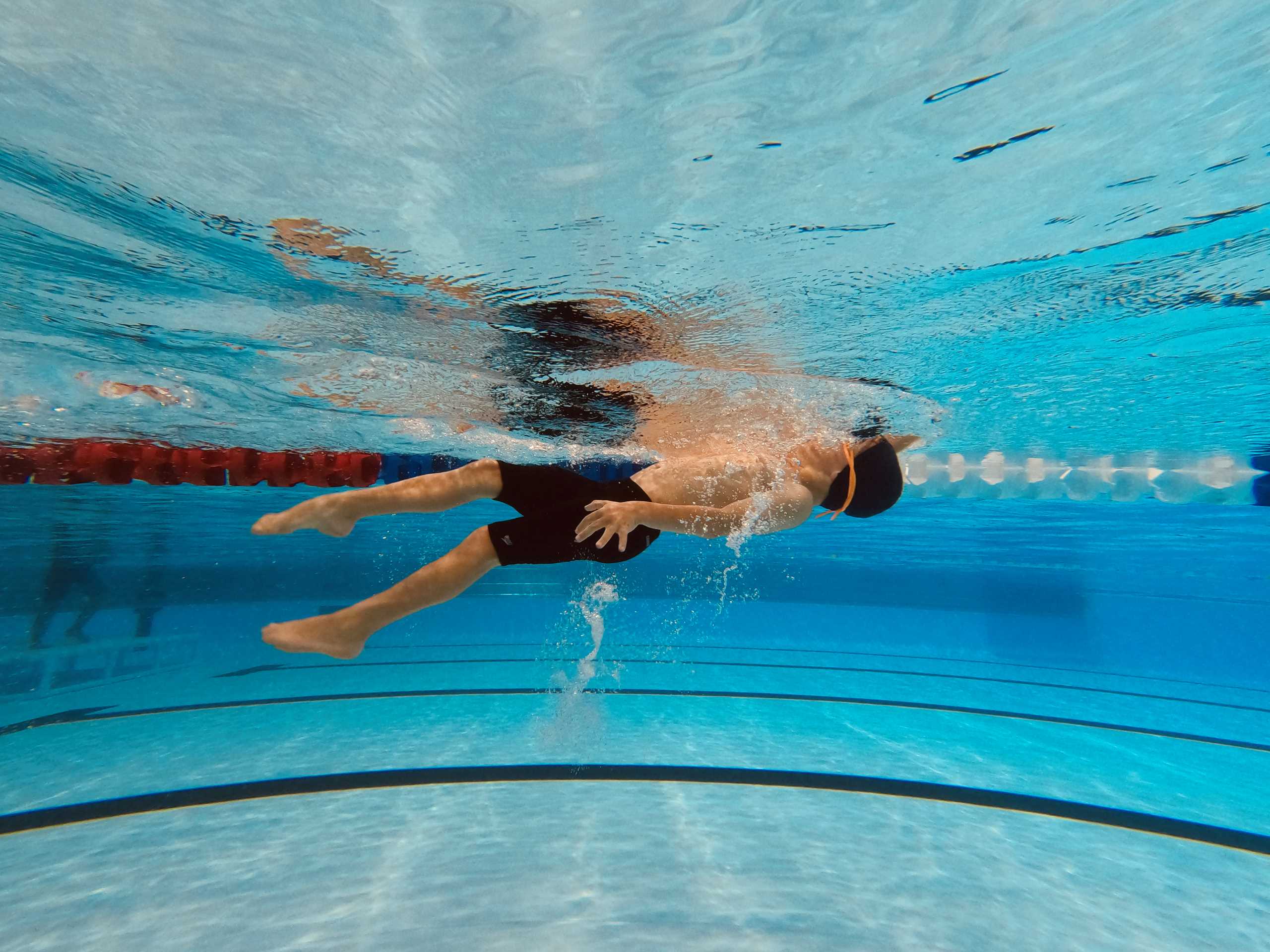 A person swimming underwater in an indoor pool - Swimming pool