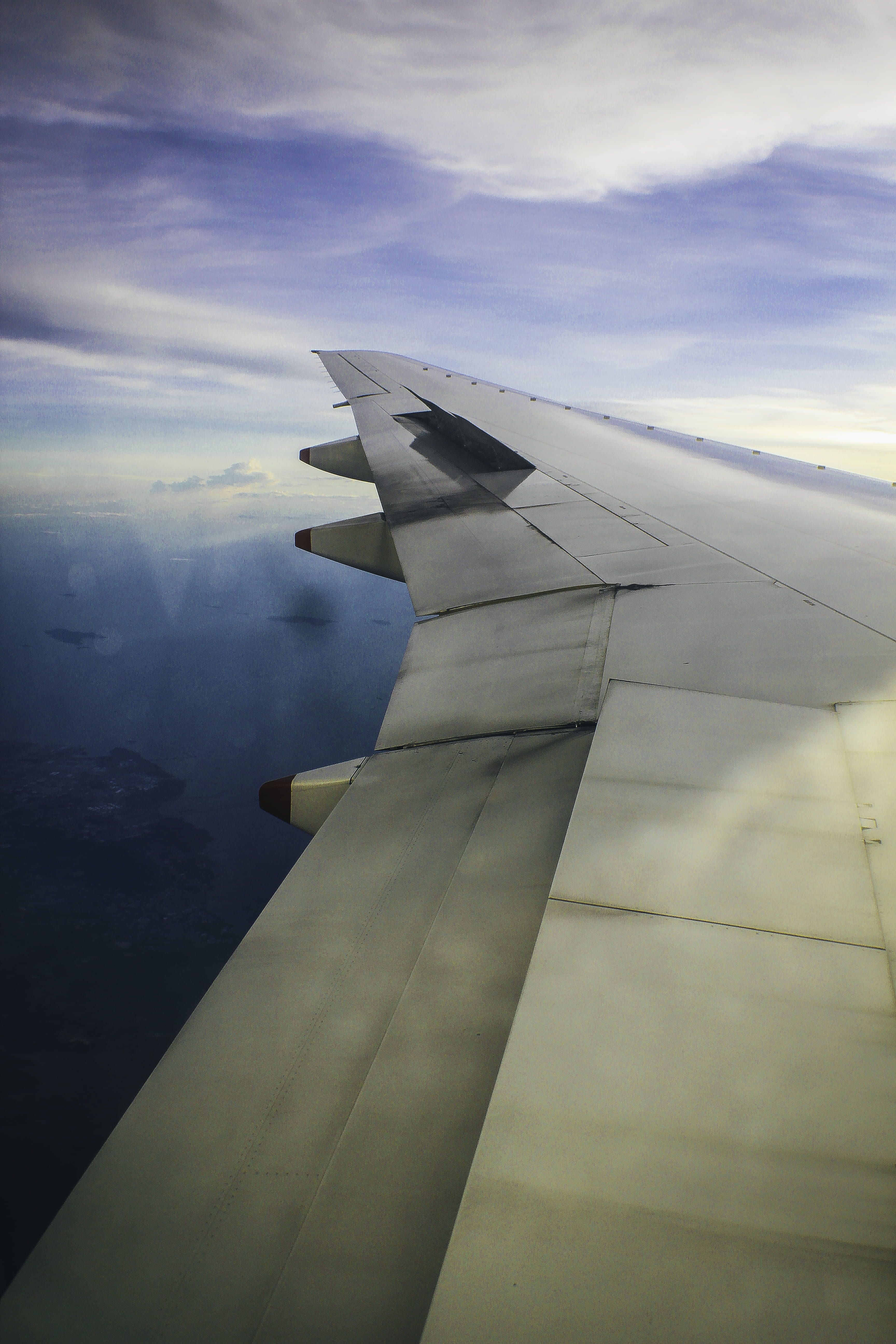 A wing of an airplane flying over the ocean - Wings, airplane