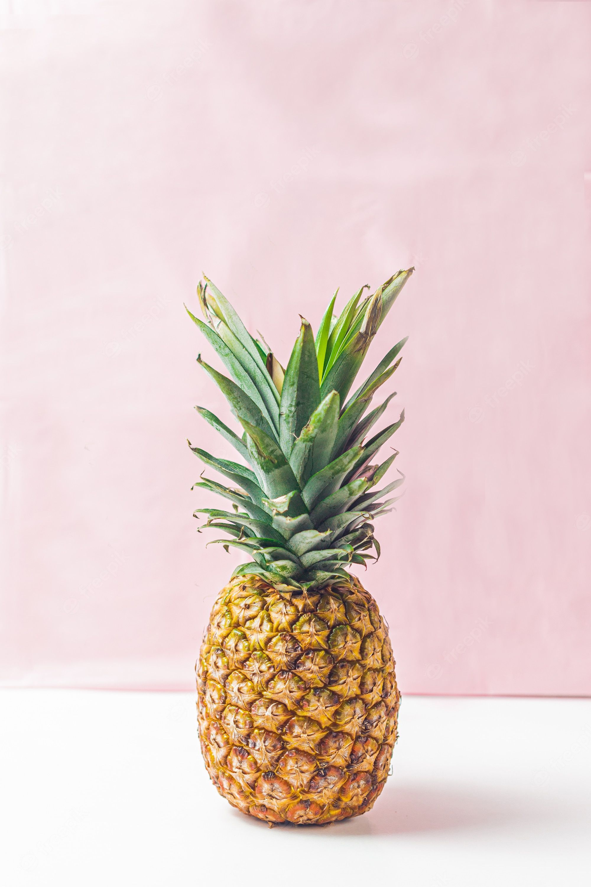 A pineapple on a white table with a pink background - Pineapple