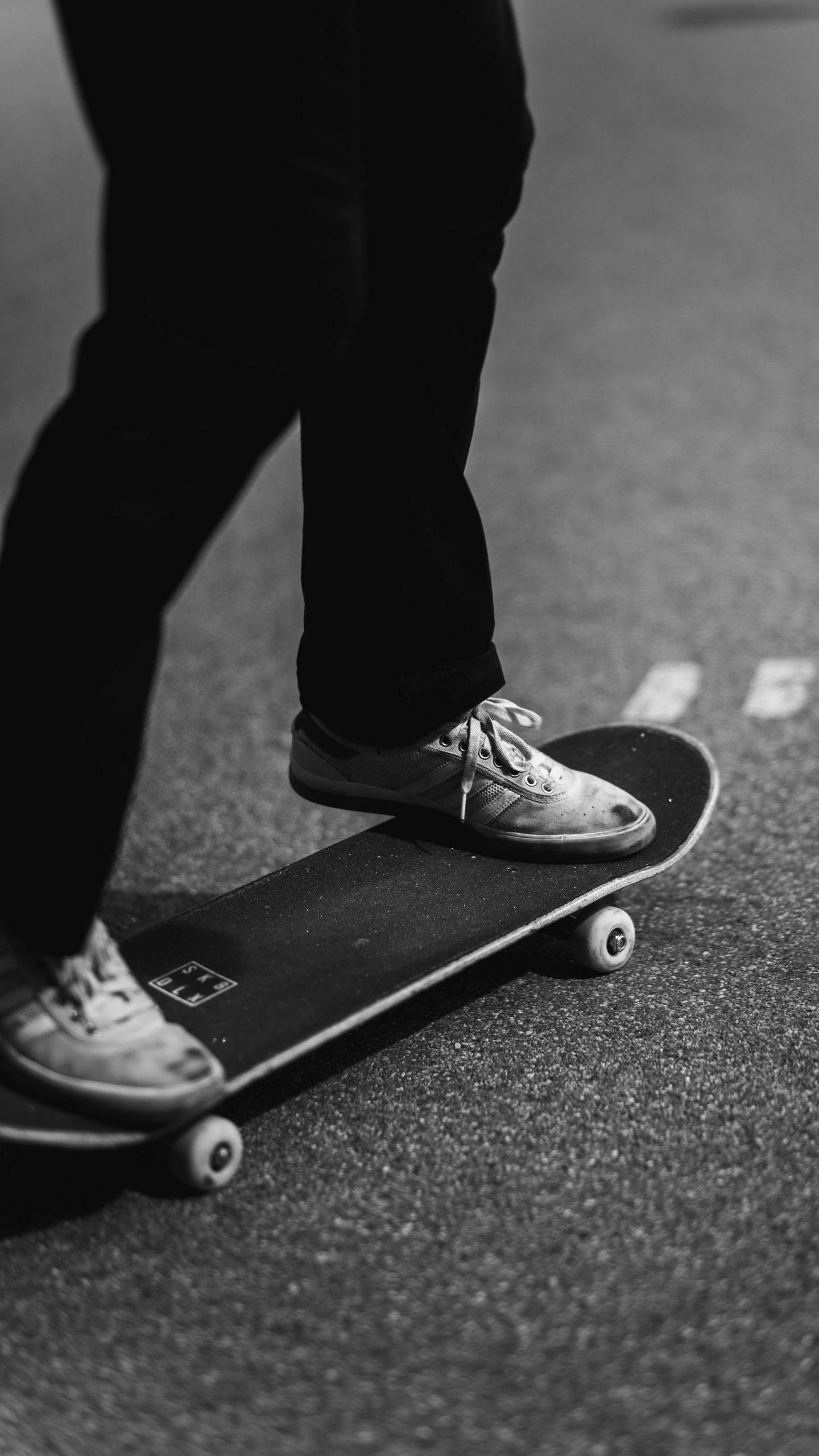 A person wearing white shoes is riding a skateboard on the street. - Skater