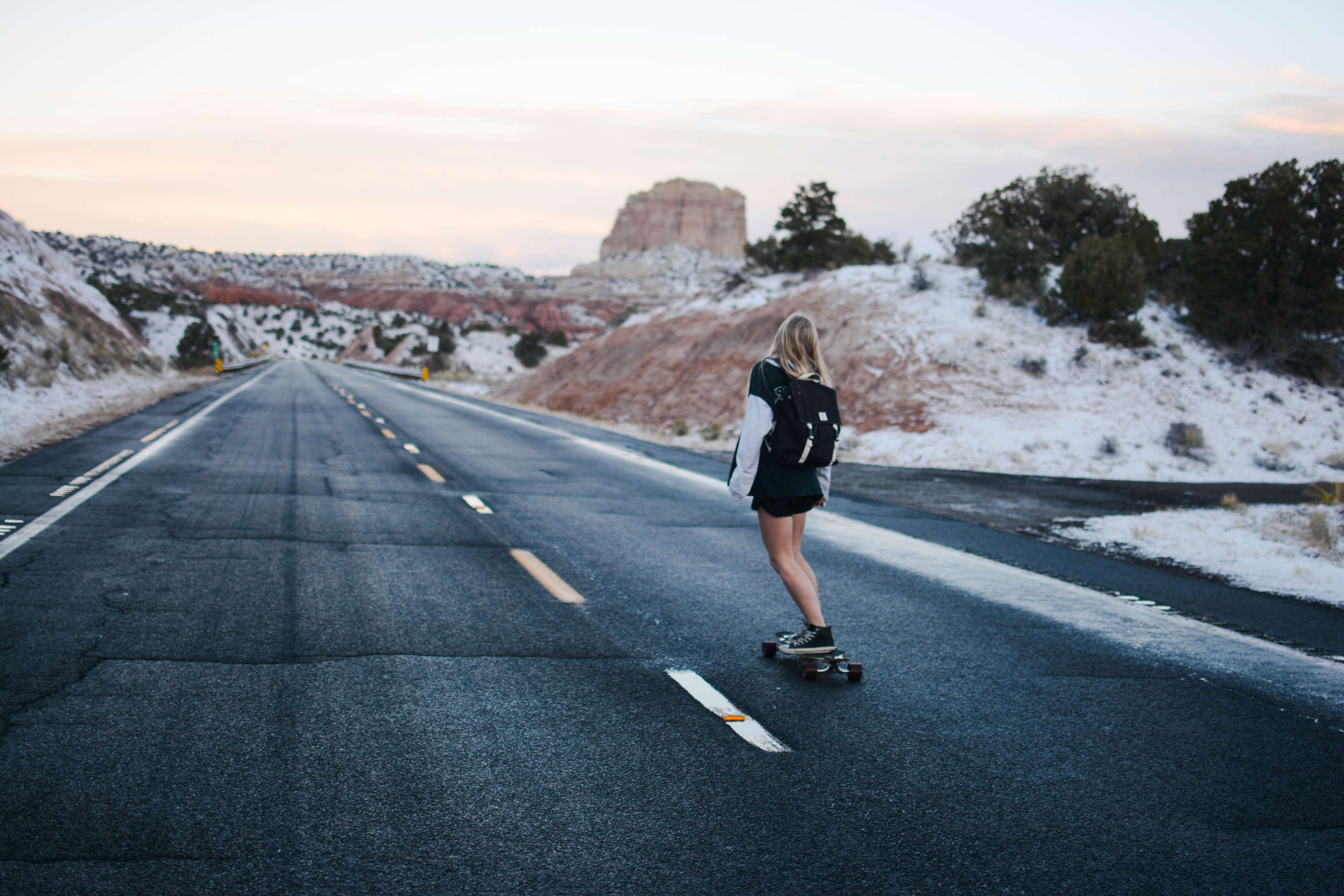 A woman skateboarding down a snowy road - Skater