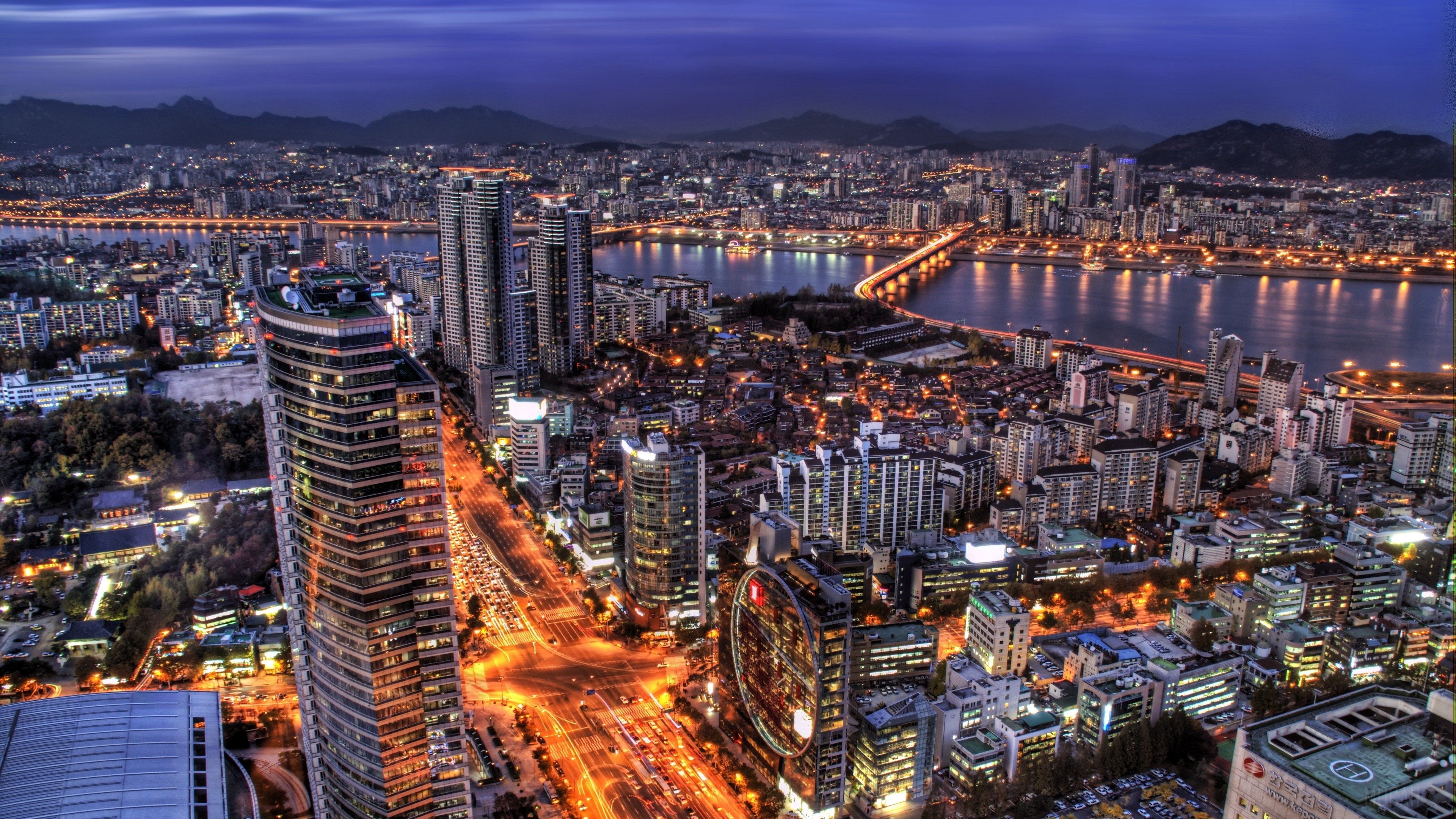 A cityscape at night with a river running through it - Seoul