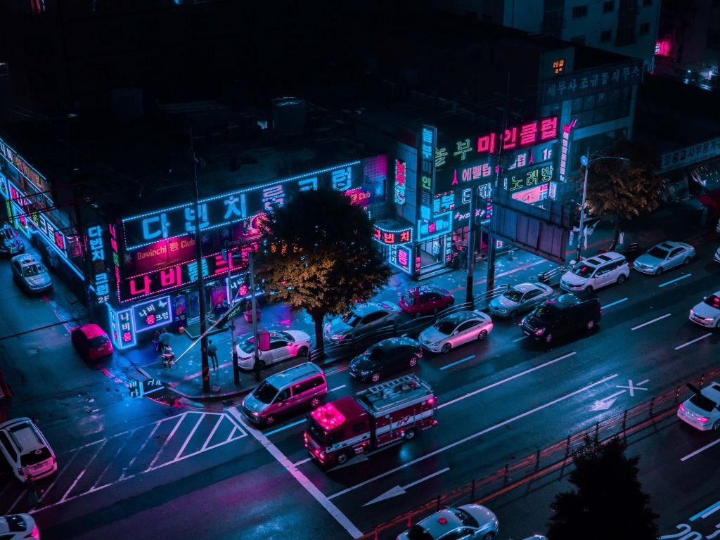 A city street at night with neon lights on the buildings - Seoul