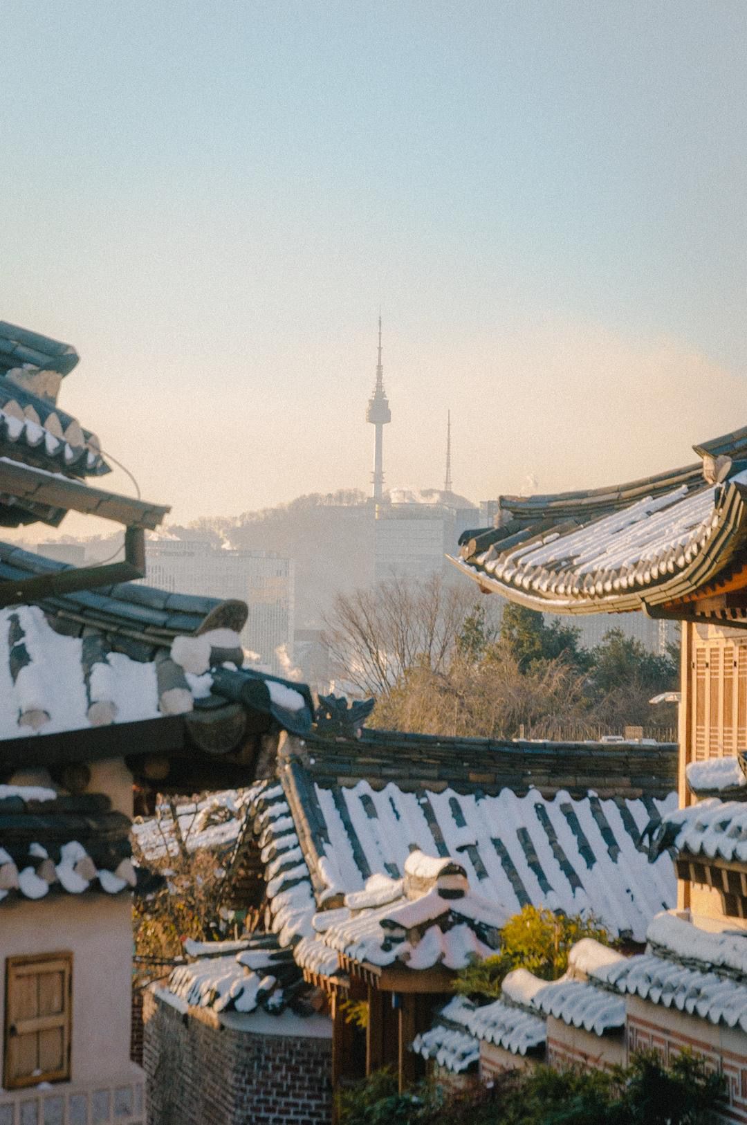 A snow-covered traditional Korean house with Namsan Tower in the background - Seoul