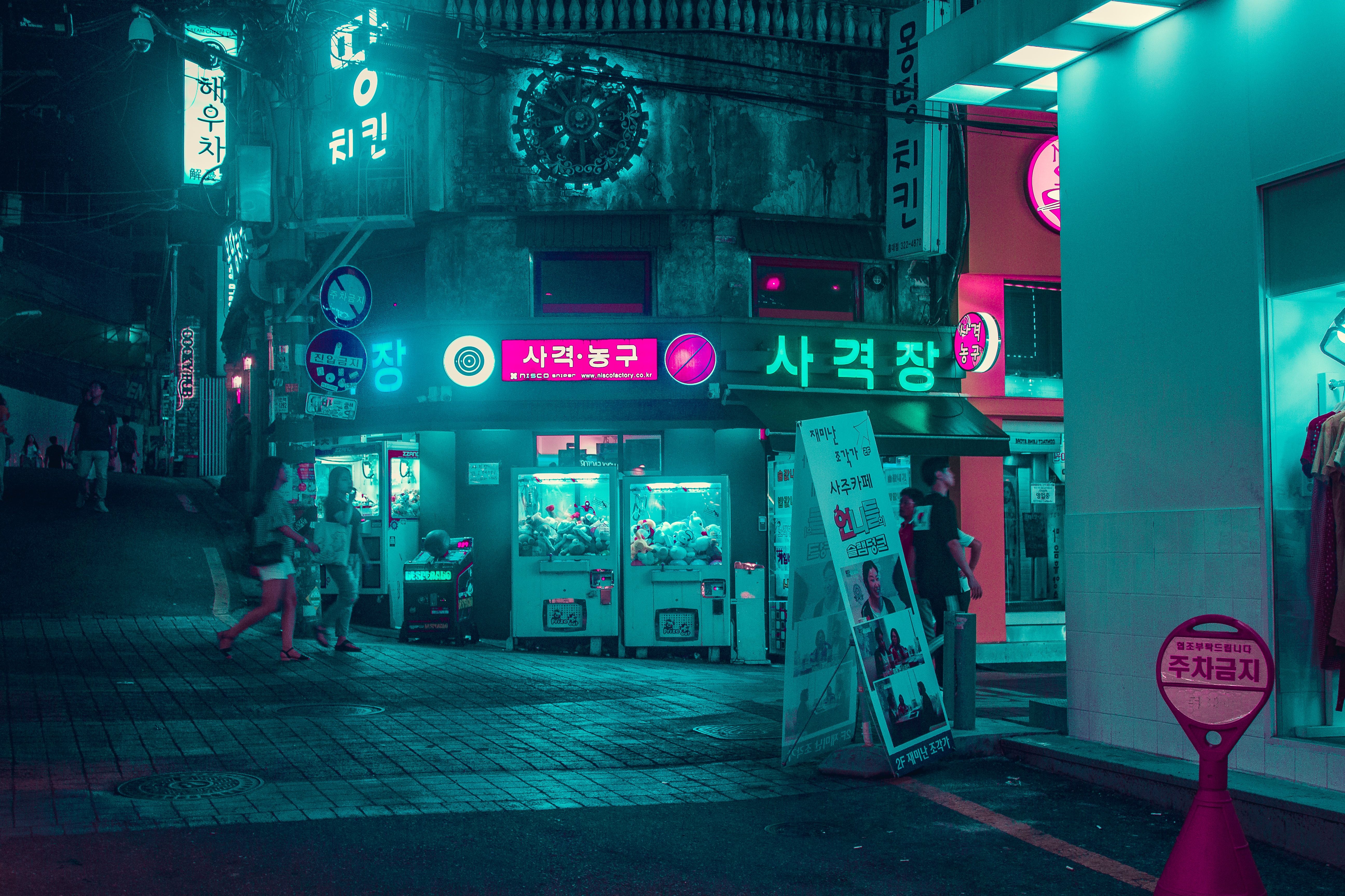 A street at night with vending machines and neon signs. - Seoul