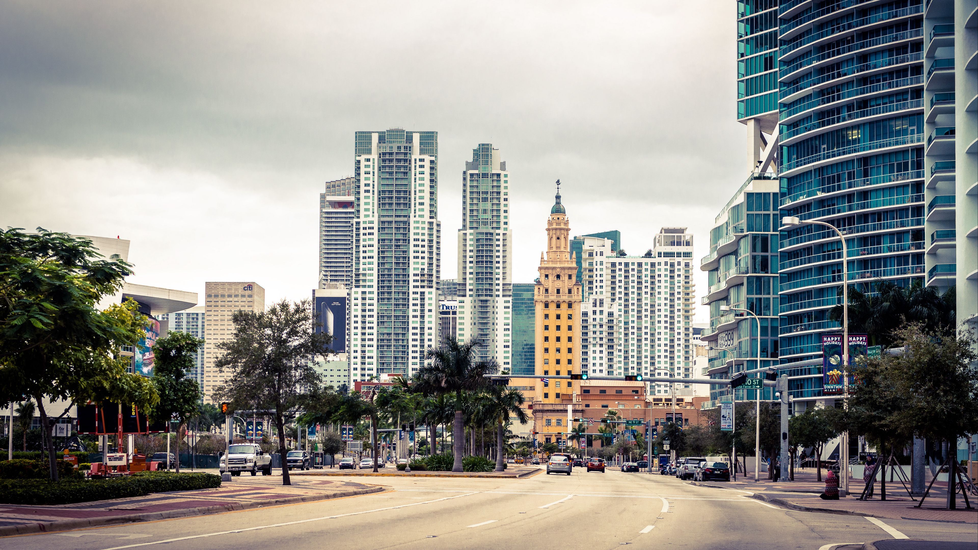 A city street with tall buildings on both sides of the road. - Miami