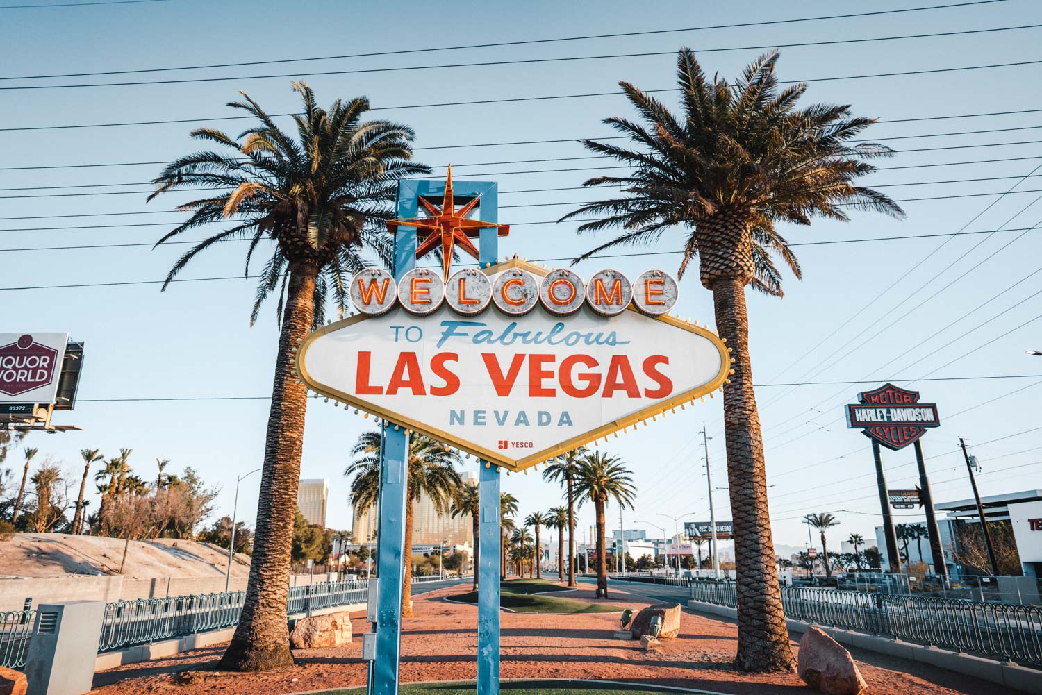 A welcome sign for las vegas is in front of palm trees - Las Vegas