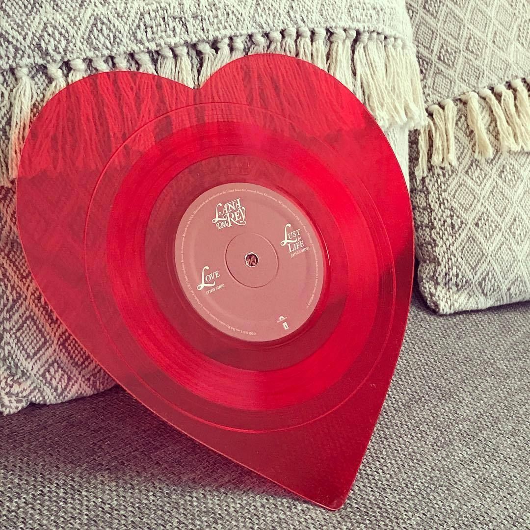 A red heart shaped vinyl record sits on the couch - Lovecore
