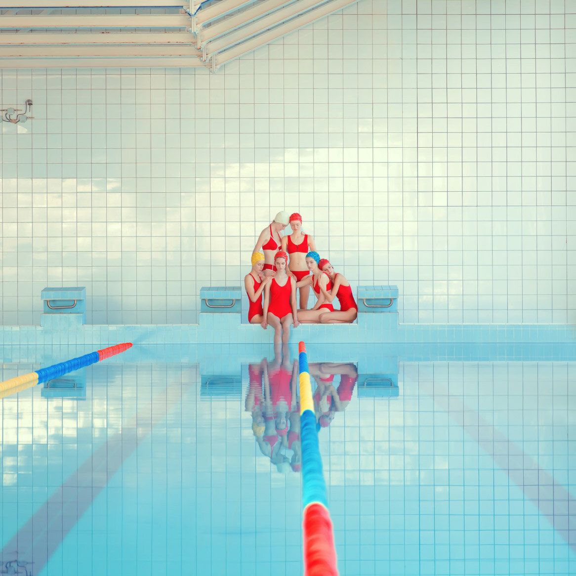 A group of people in red swimsuits standing on the edge - Swimming pool