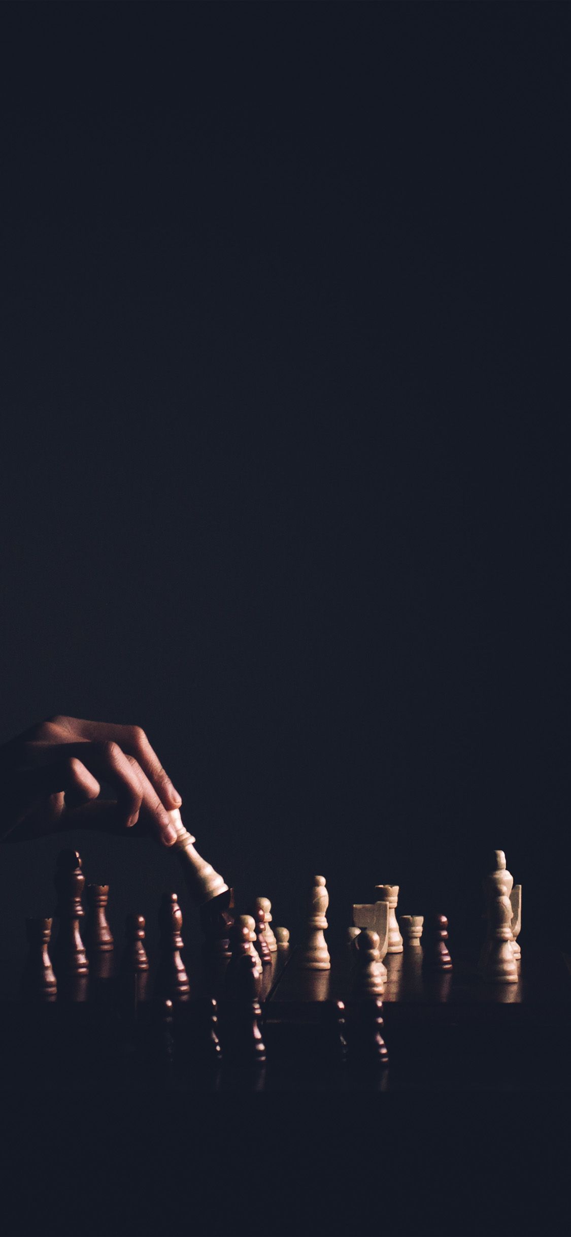 A hand moves a chess piece on a board - Chess