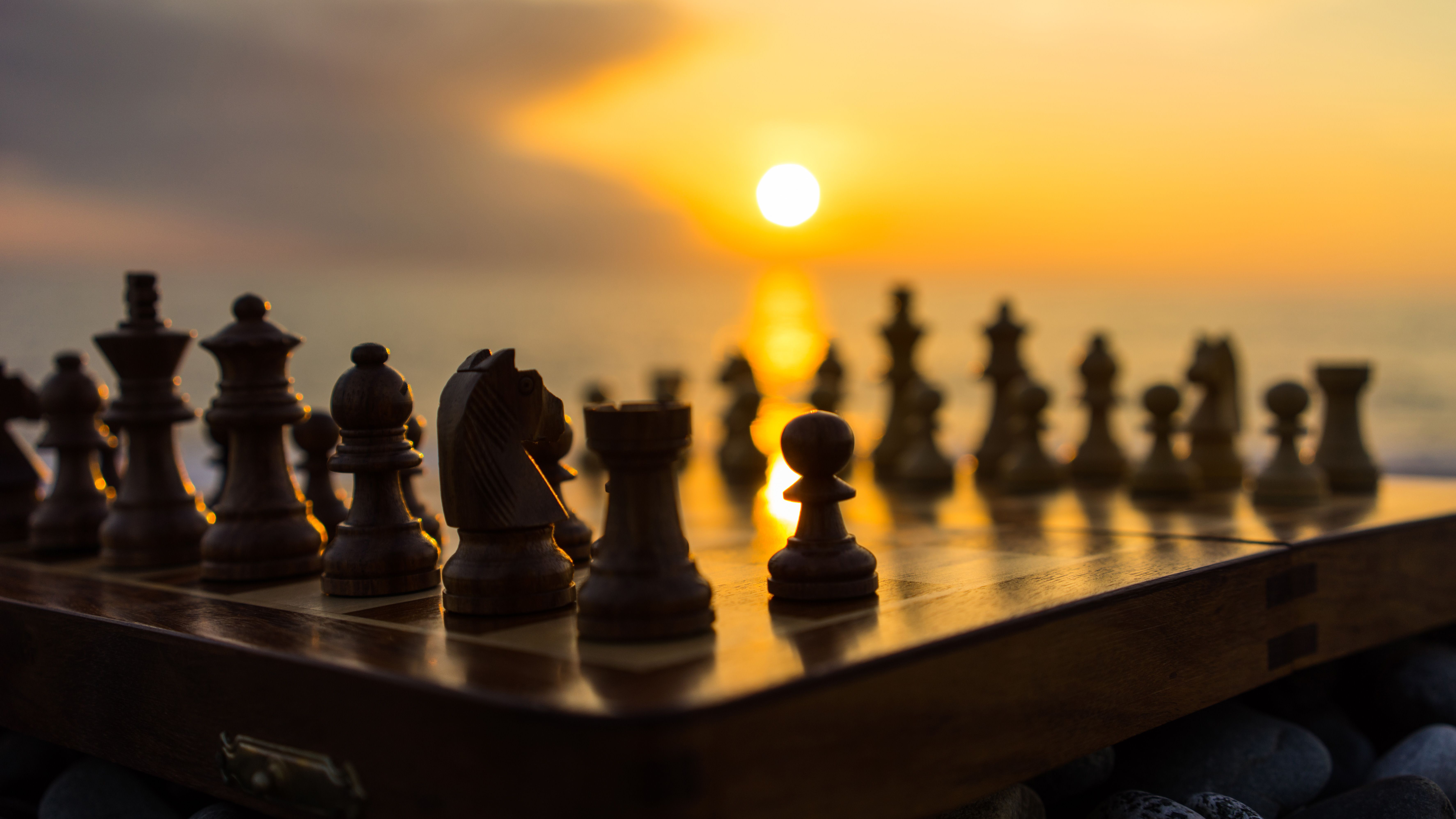 A chess board with pieces on it in the sun - Chess