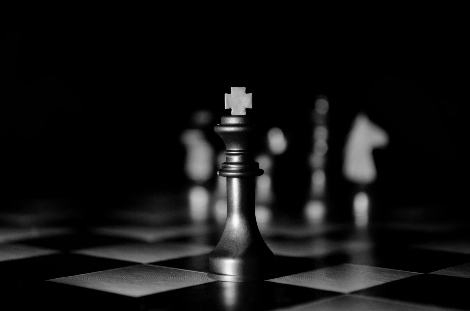 A black and white photo of a chess board with a black king in the foreground. - Chess