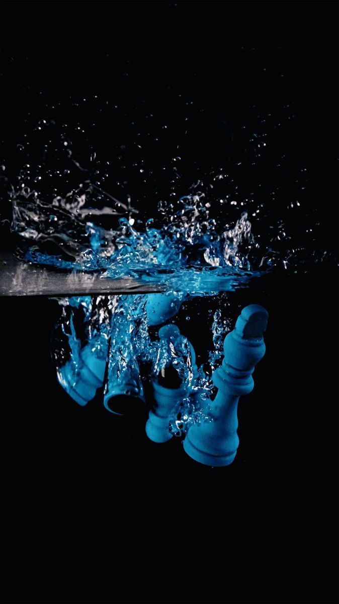 A black background with a blue chess piece falling into water. - Chess