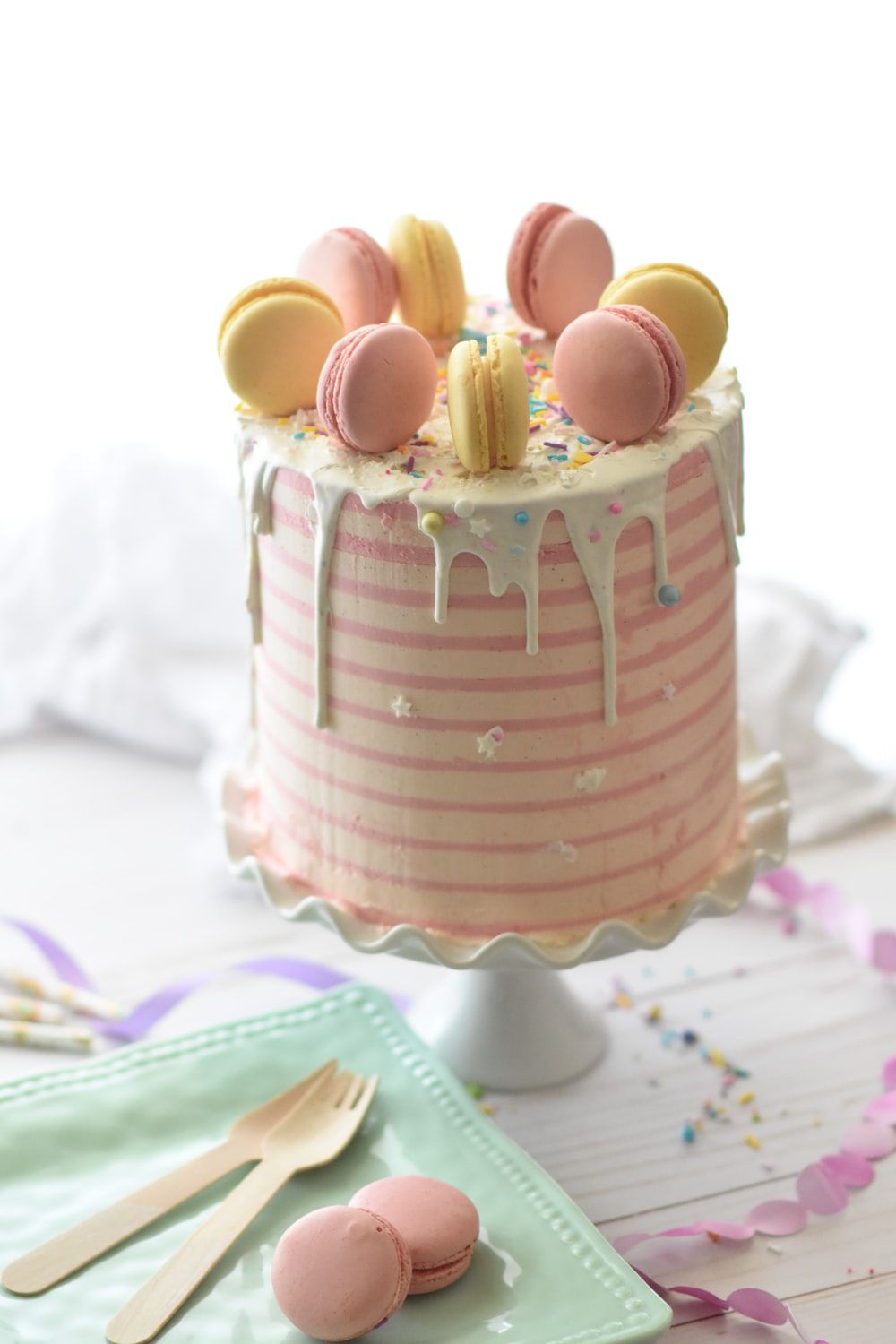 A cake with macarons on top and sprinkles. - Cake