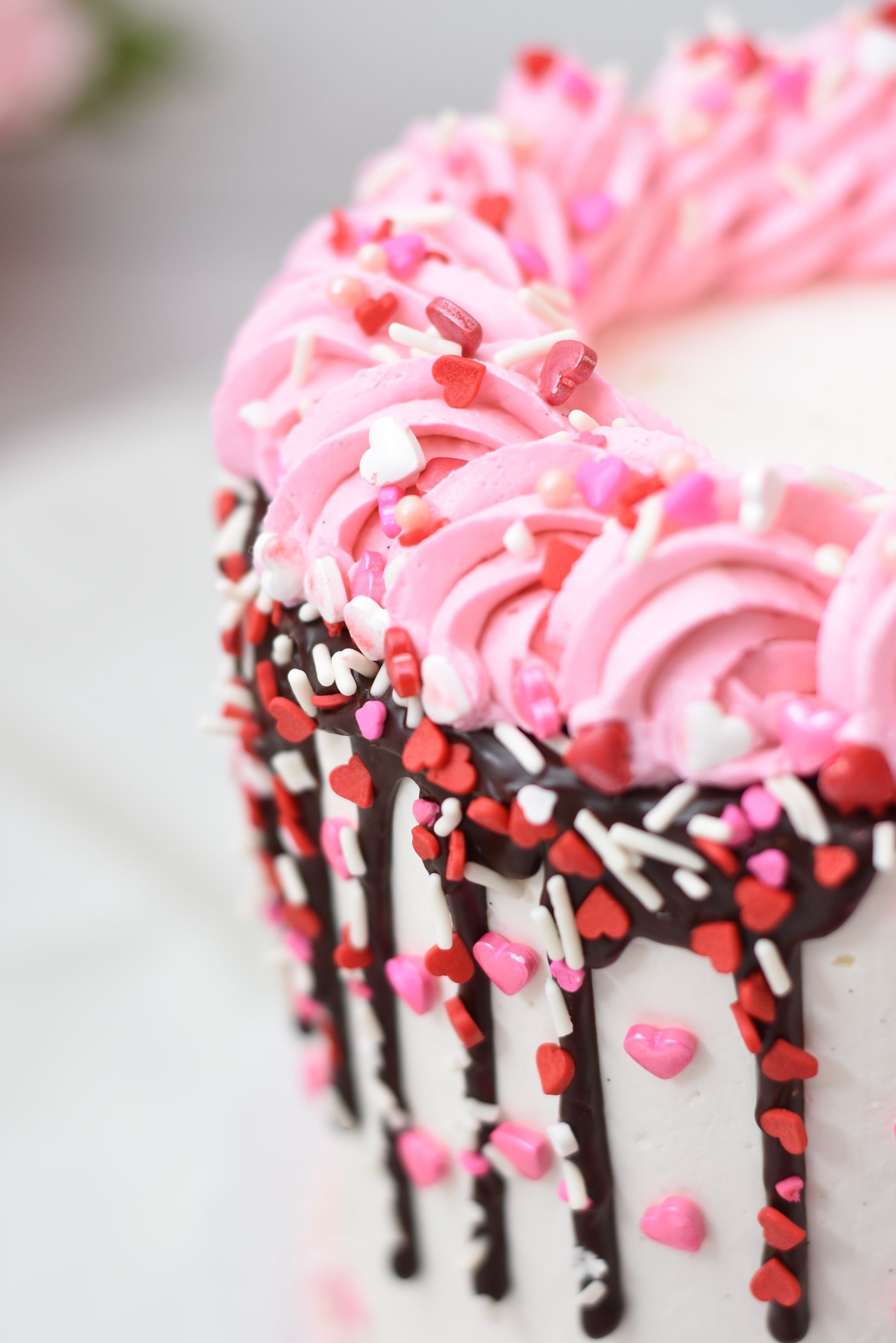 A cake with pink frosting and sprinkles on it. - Cake