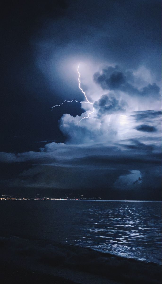 A lightning bolt strikes in the distance over the ocean - Storm
