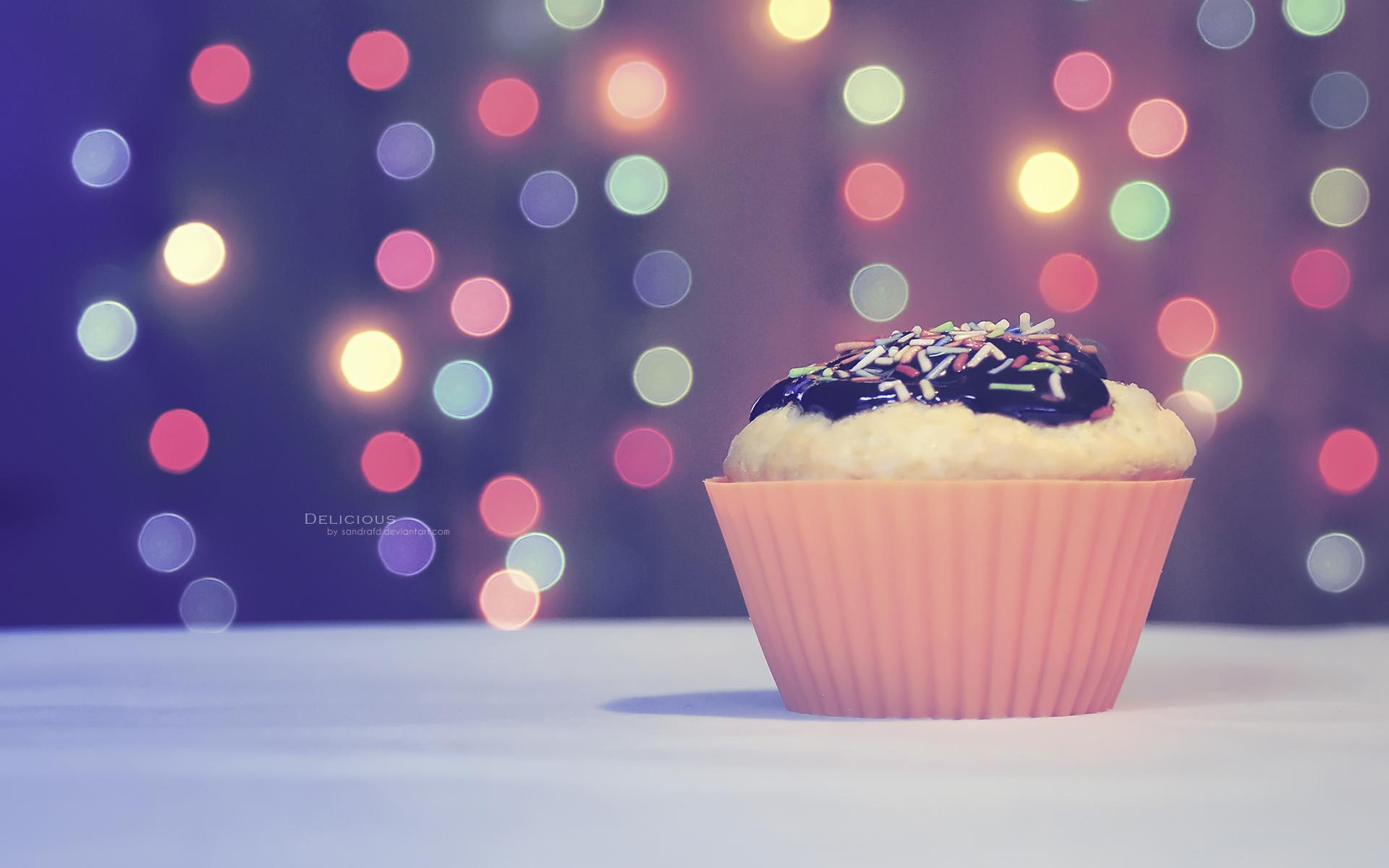 A cupcake with sprinkles on a table with a colorful background. - Cake, cupcakes