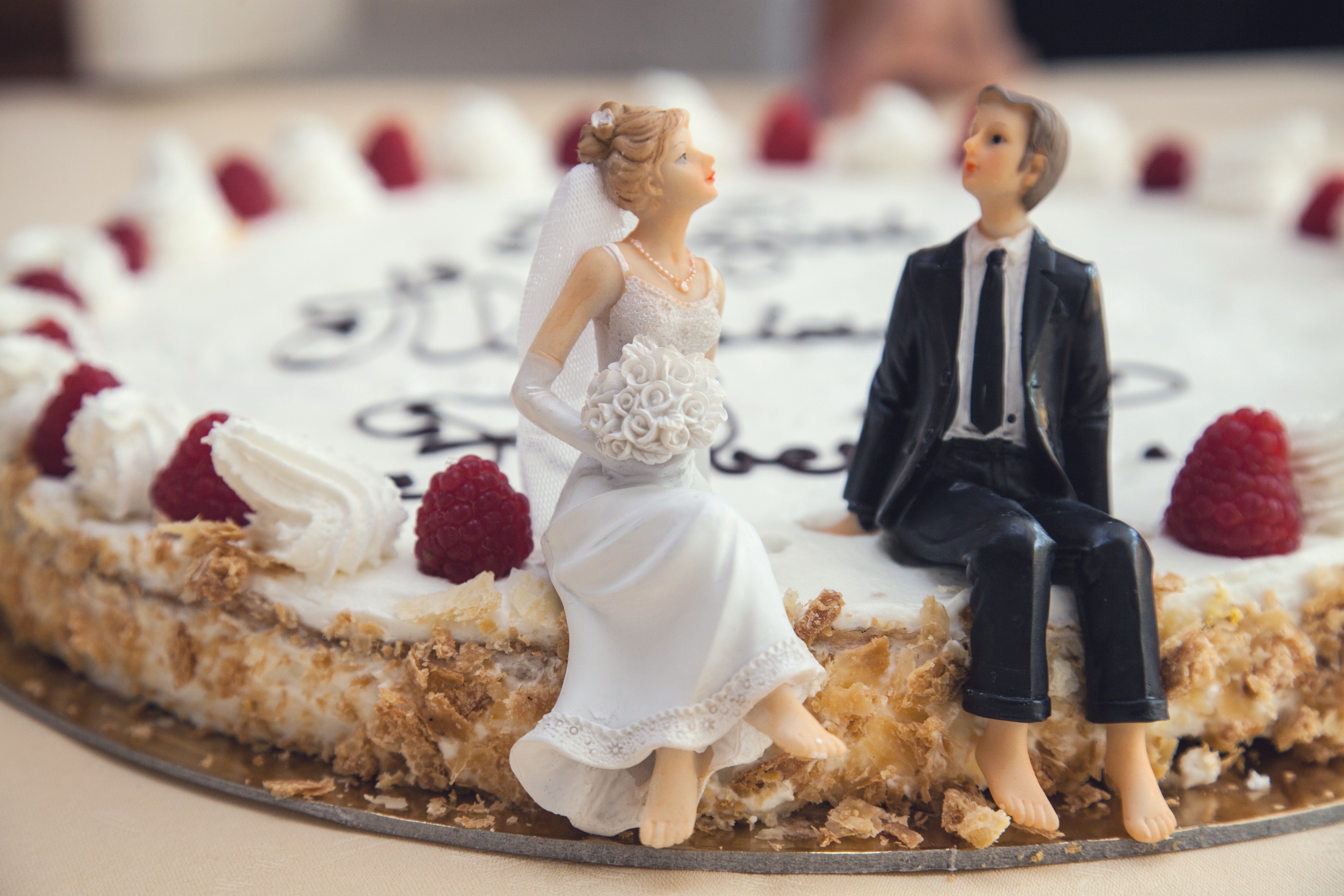 A wedding cake with a bride and groom figurine sitting on it. - Cake