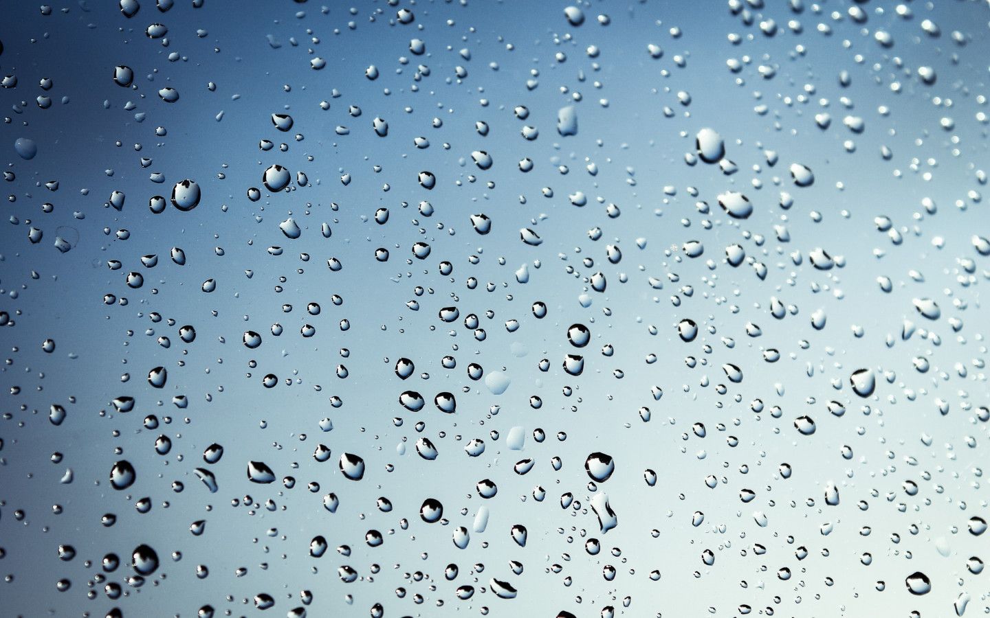 Raindrops on a window, with a blue sky in the background - 1440x900