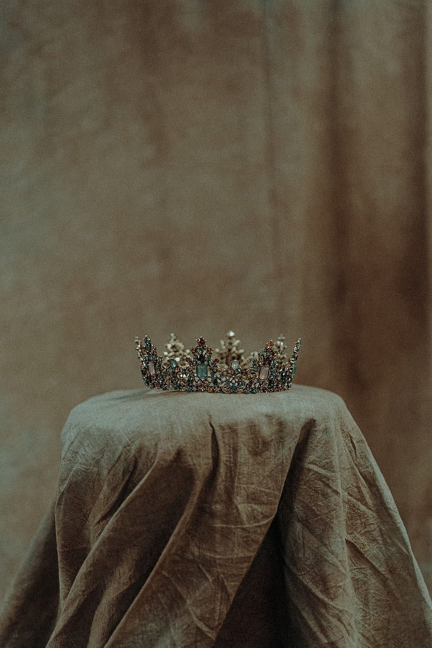 A crown sits on a table clothed table. - Crown