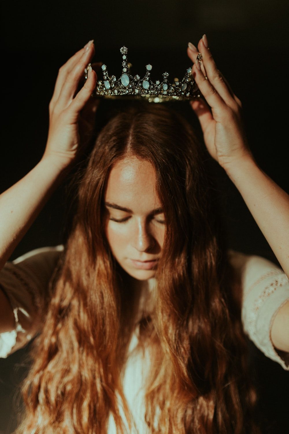 A woman with long hair holding up her head - Crown