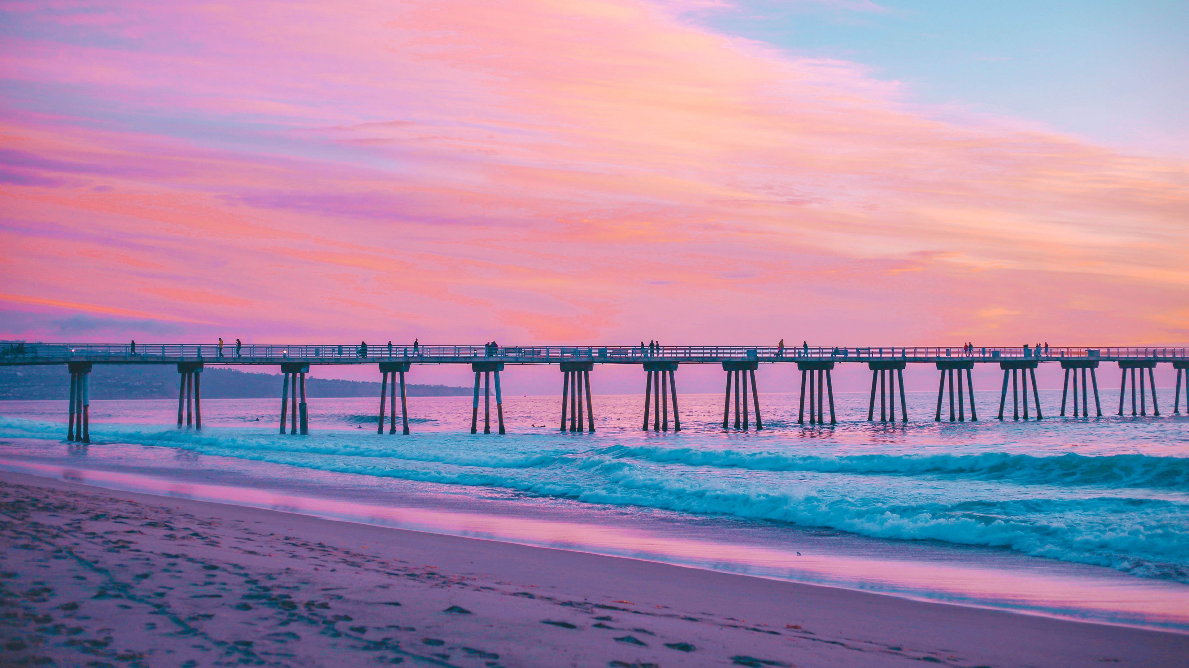 A pier stretches out into the ocean at sunset. - Surf