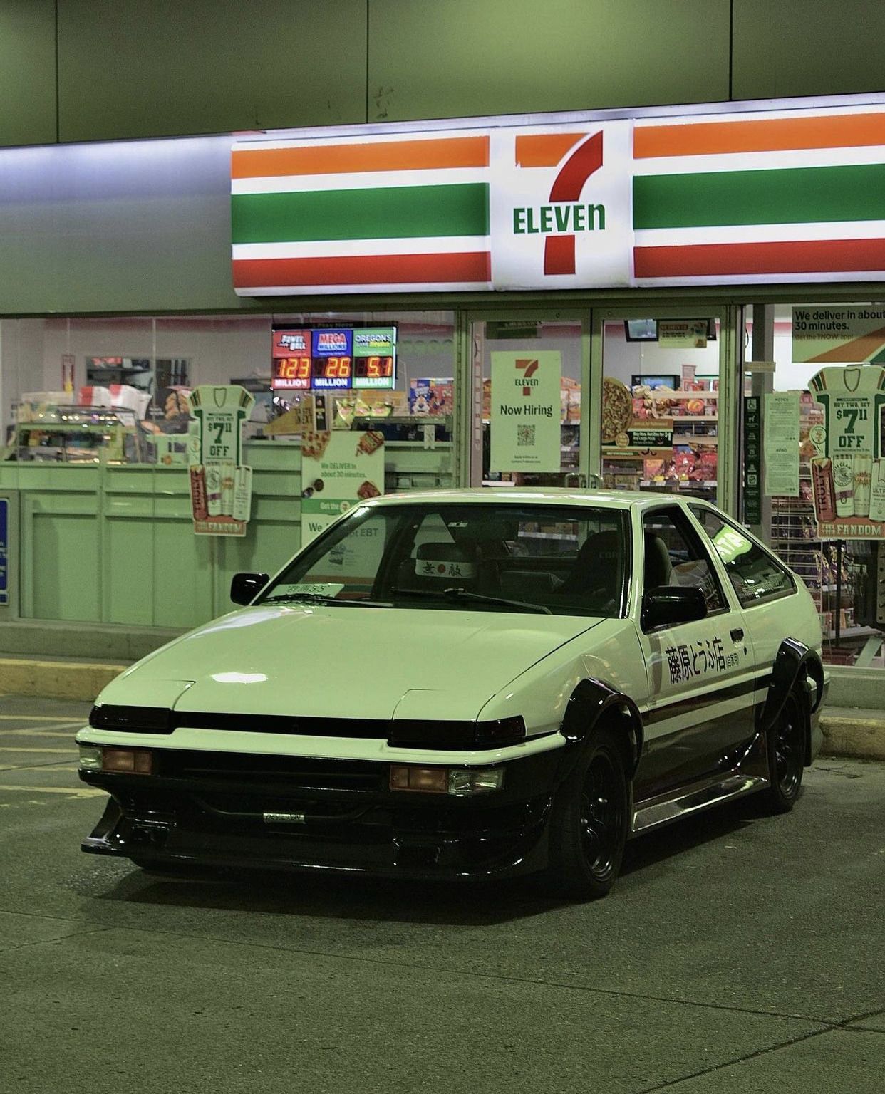 A white car parked in front of a 7-11 - Toyota AE86