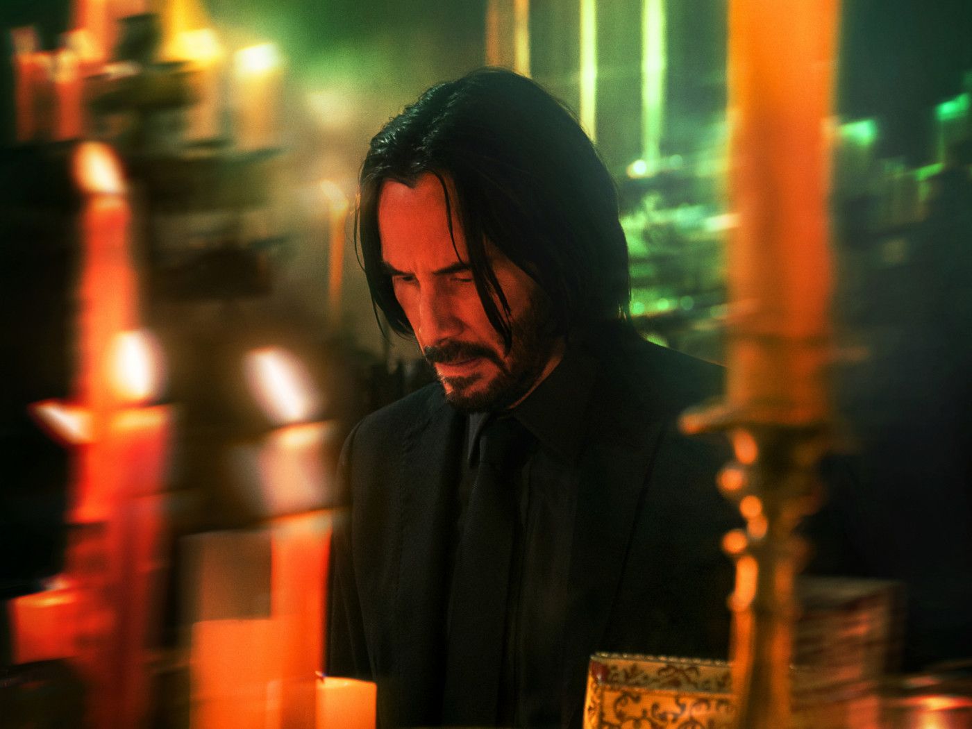 A man with long hair and black suit is standing in front of candles - Sad, dog
