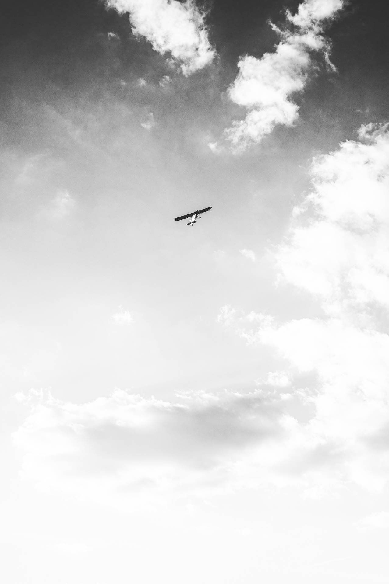 A small plane flying through a cloudy sky. - 