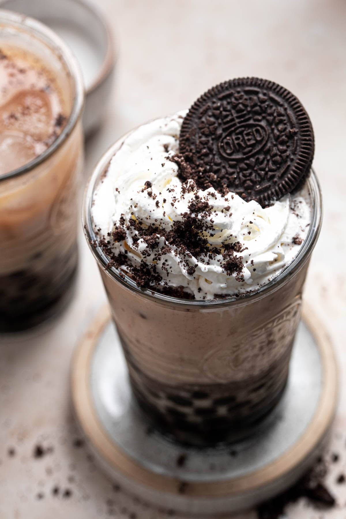 A glass of Oreo Frappuccino topped with whipped cream and an Oreo cookie. - Oreo