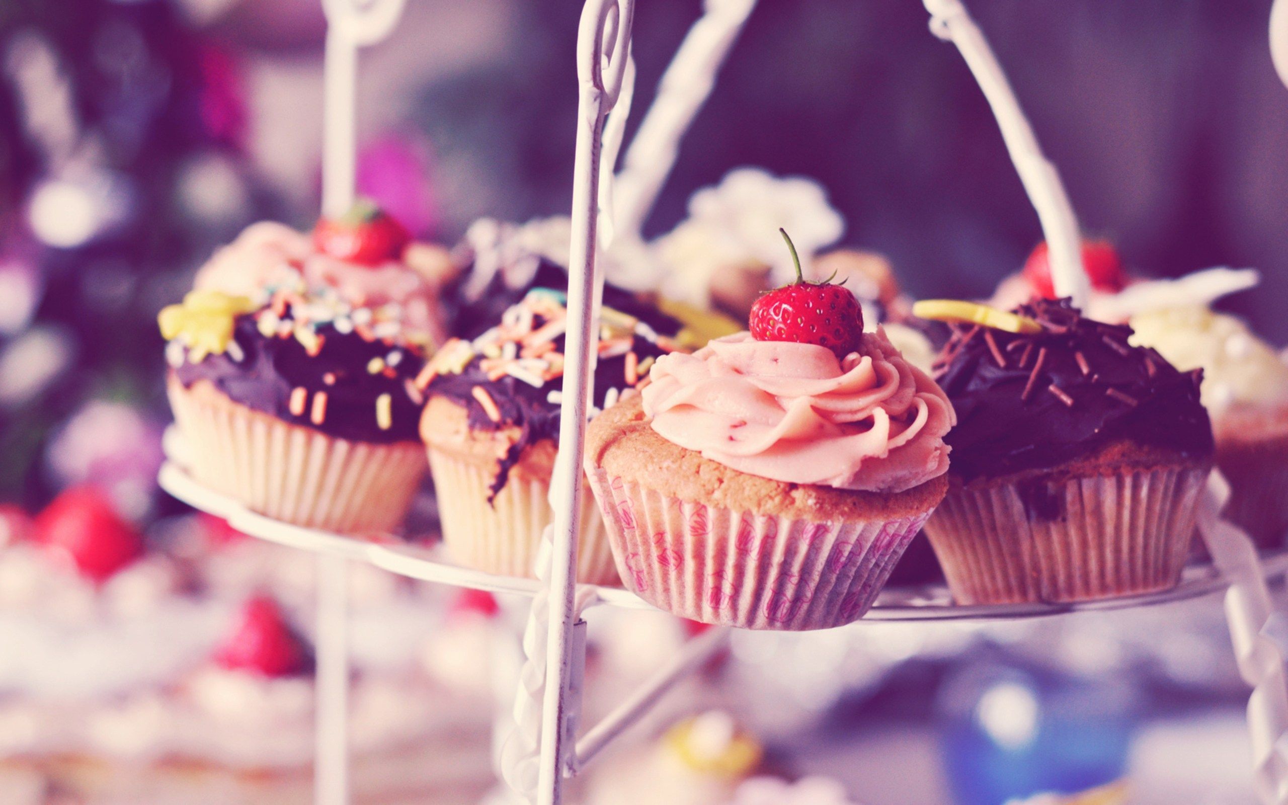 A white cake stand with four cupcakes on it. - Cupcakes