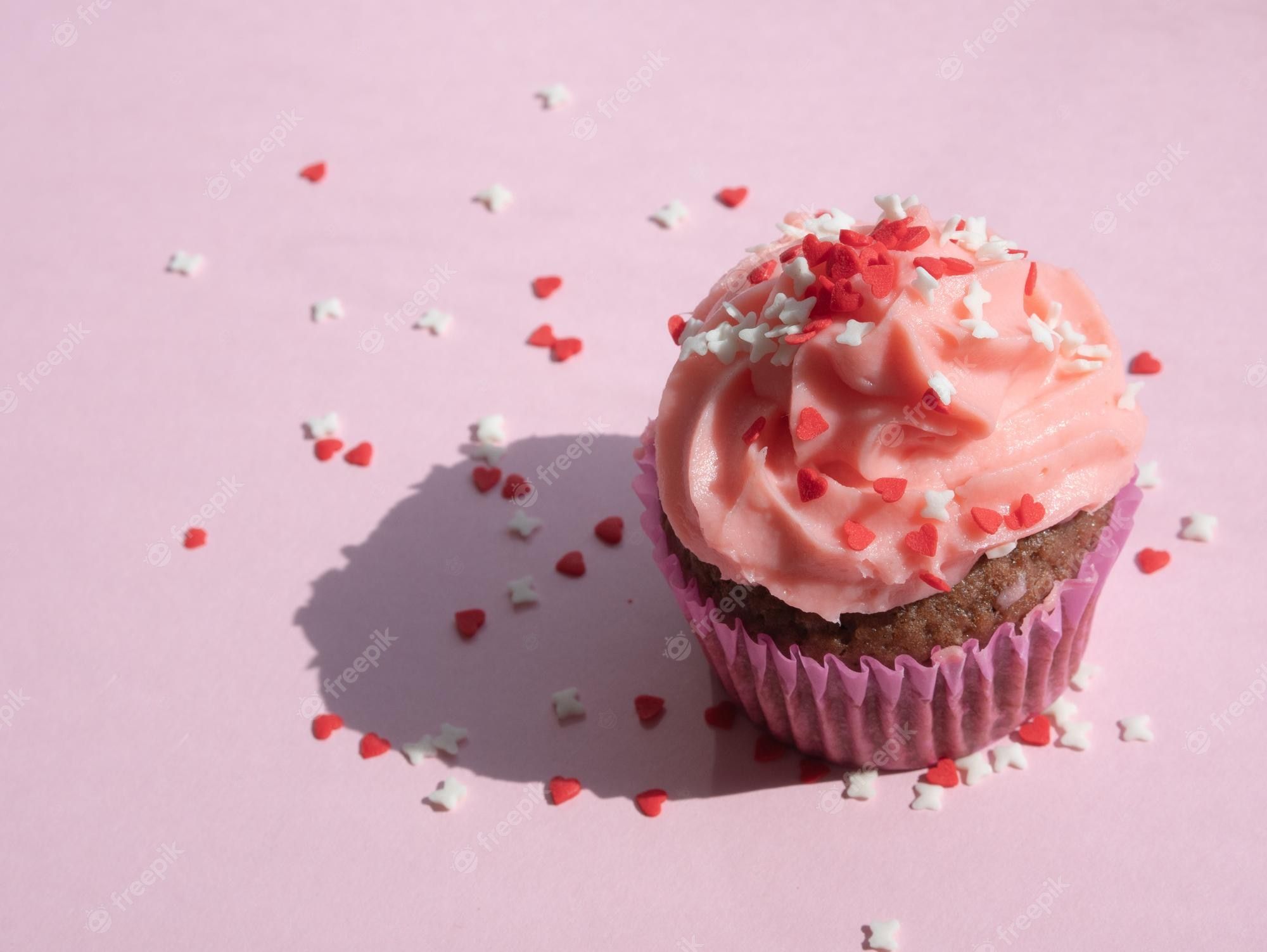 A pink cupcake with sprinkles on a pink background - Cupcakes