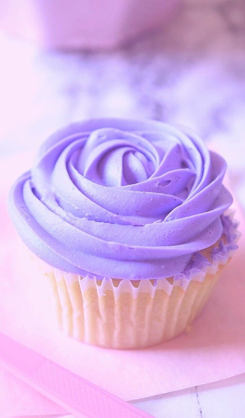 A purple frosted cupcake on a pink napkin. - Cupcakes