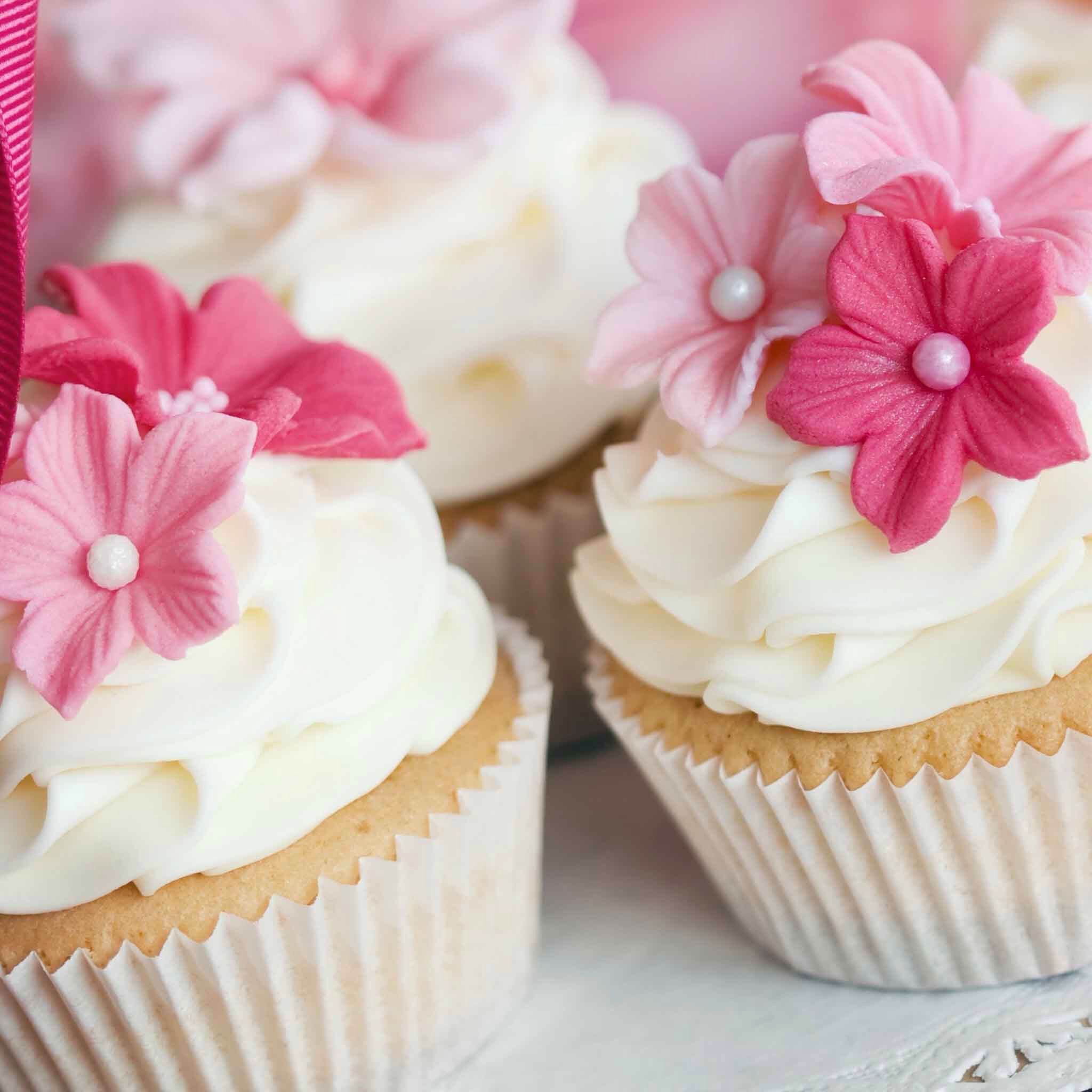 A close up of cupcakes with pink flowers on top - Cupcakes