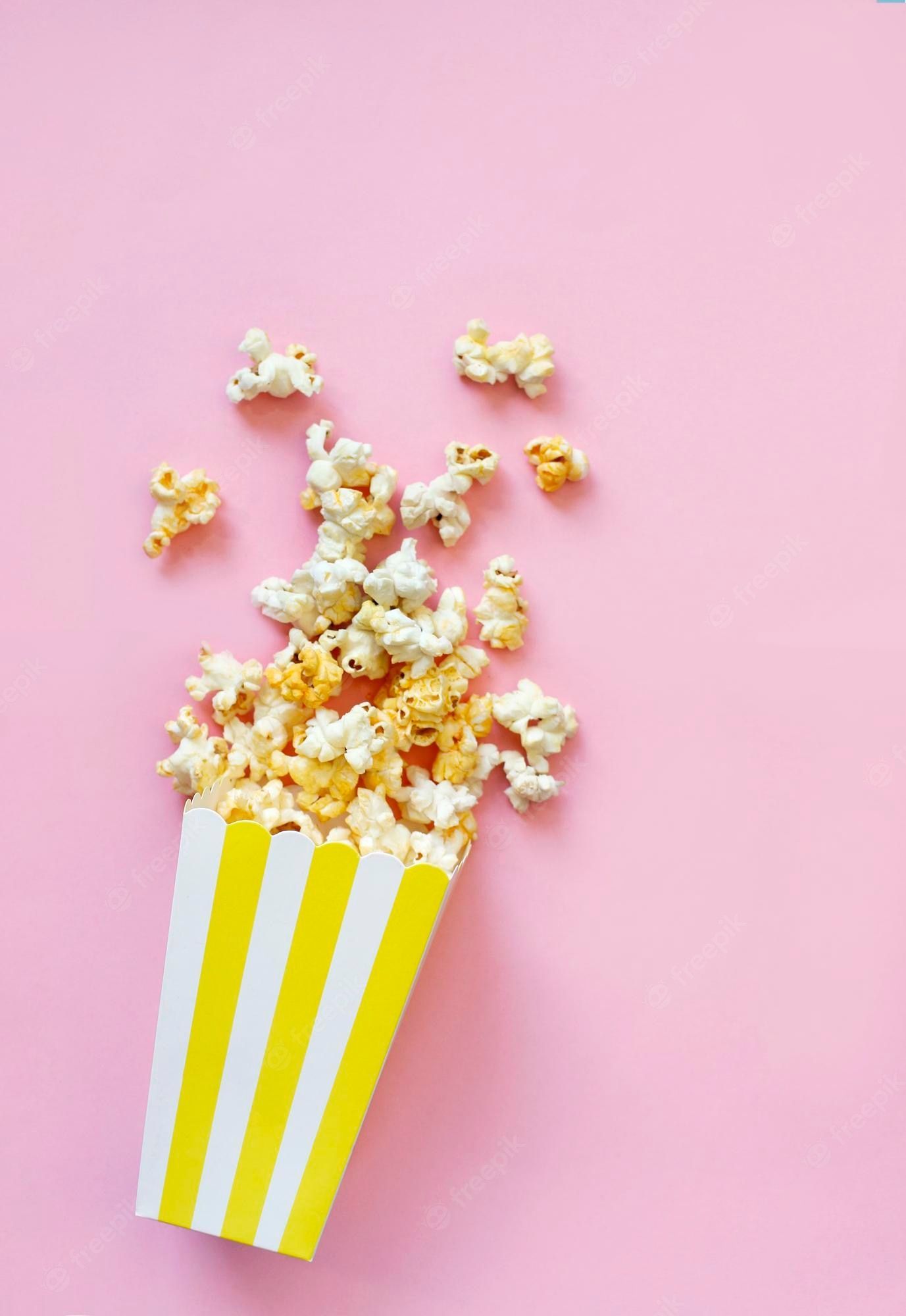 Premium Photo. Spilled popcorn on pink background movie night concept copy space for text