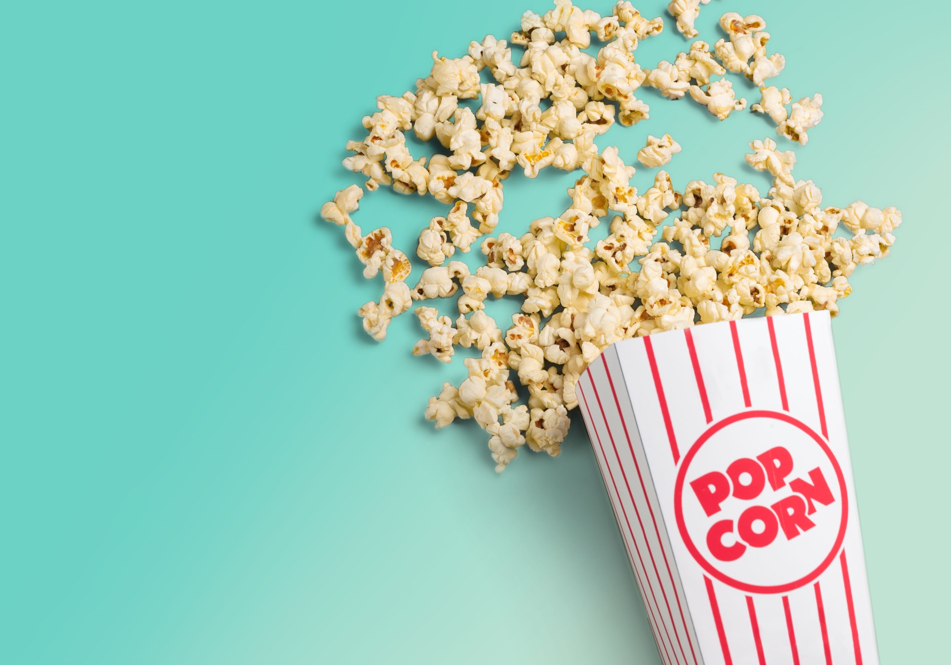 A bucket of popcorn spilling out onto a green background - Popcorn