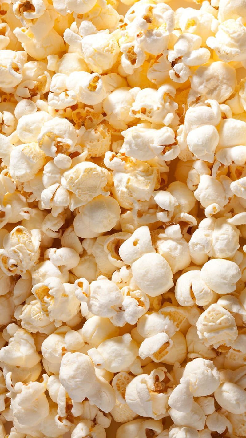 A close up of popcorn, with a pile of it in the foreground. - Popcorn