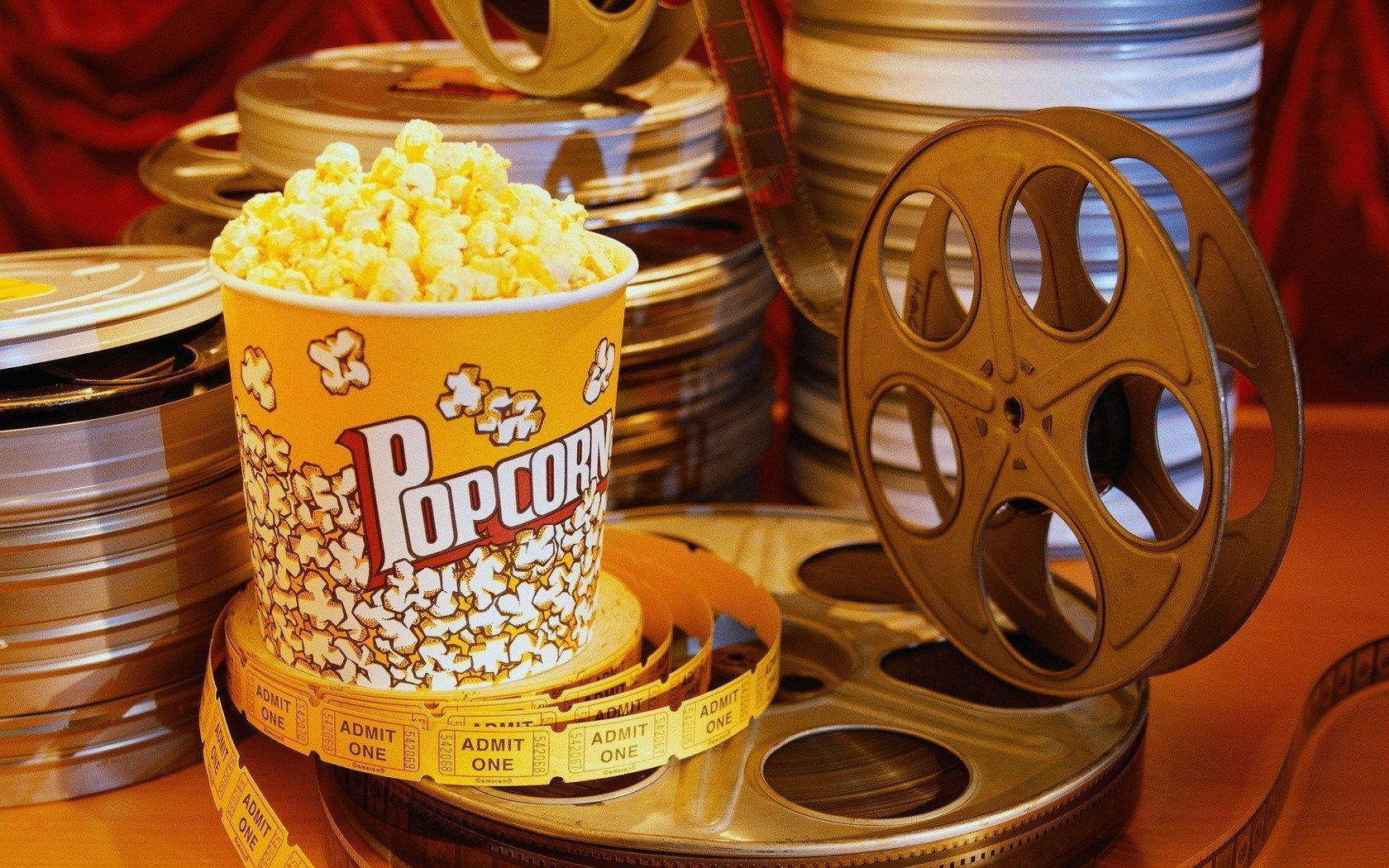 A cup of popcorn sits next to film reels - Popcorn