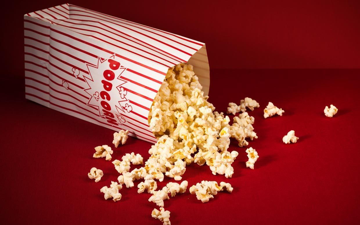 Popcorn spilling out of a popcorn bag on a red background - Popcorn