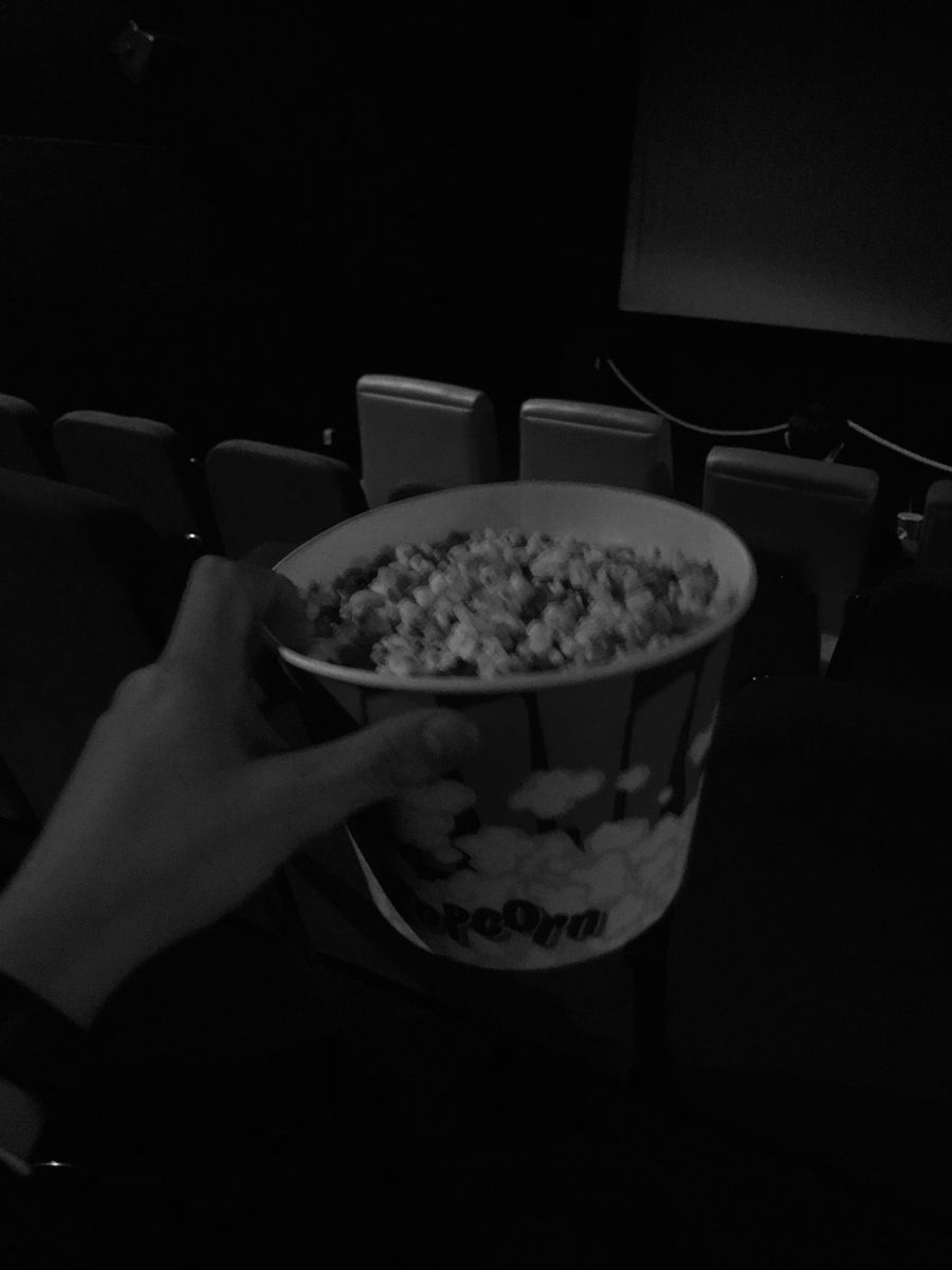 A person holding up some popcorn in front of them - Popcorn