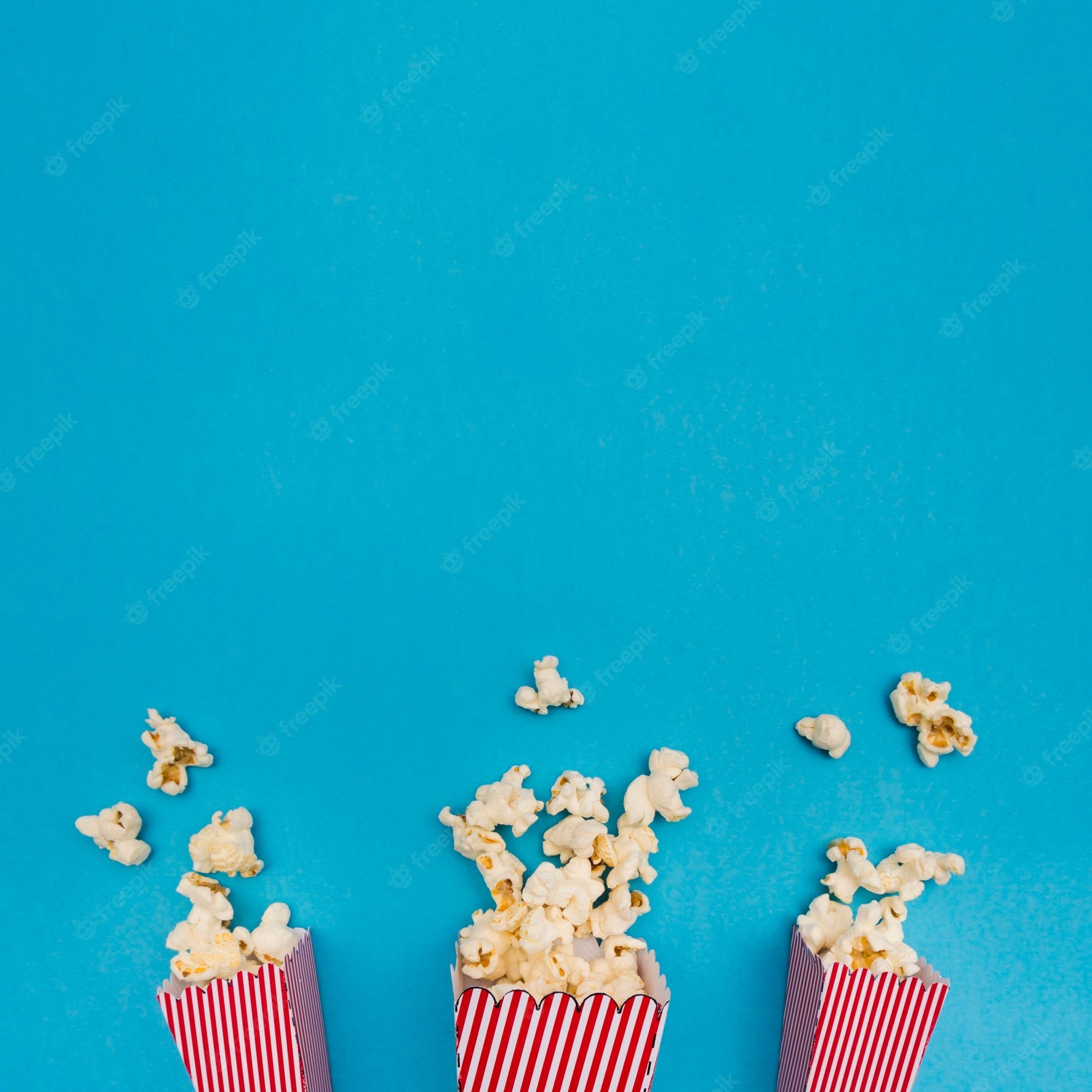 Popcorn in red and white striped buckets on a blue background - Popcorn
