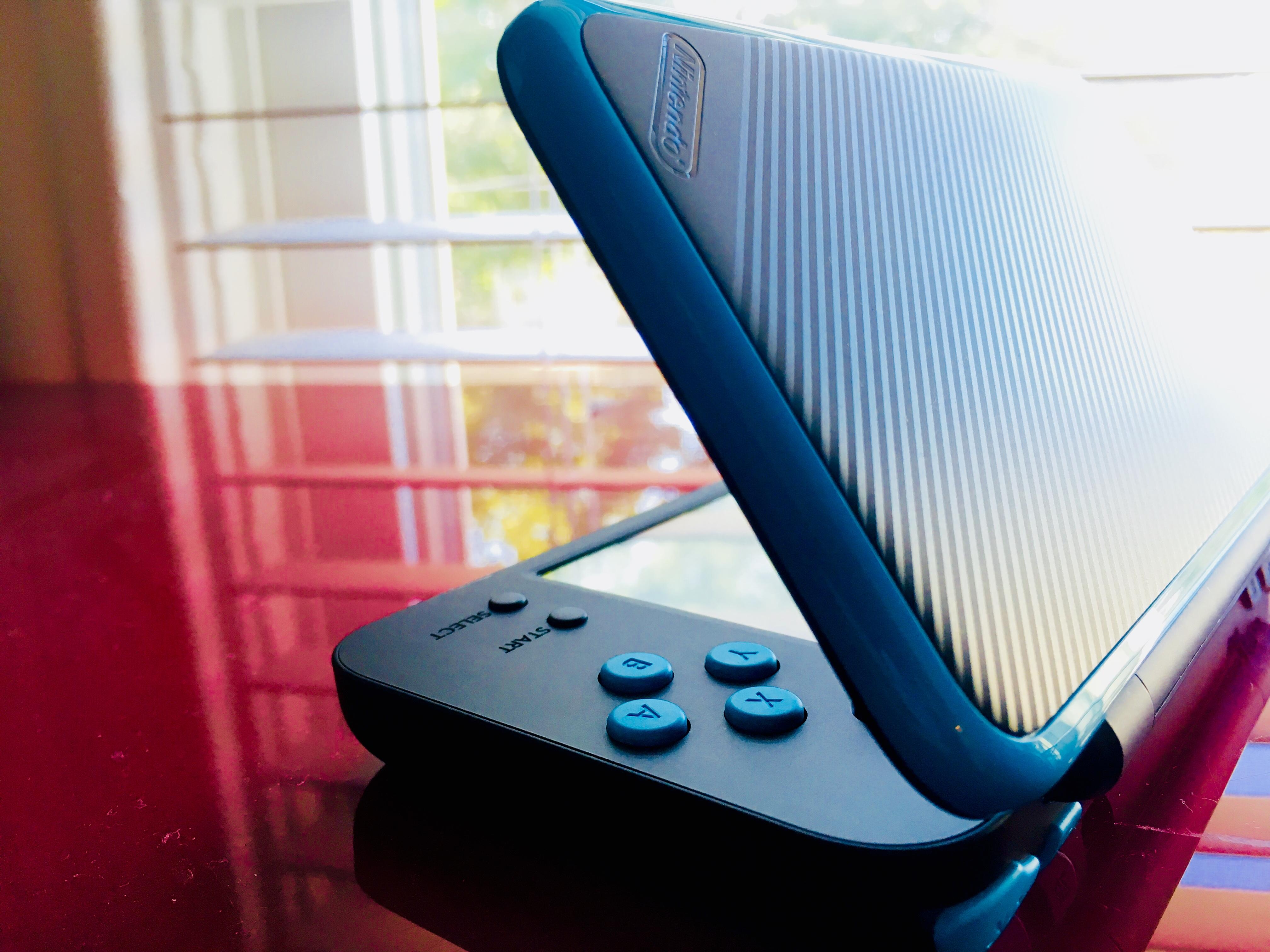 A blue and black game system sitting on top of something - Nintendo