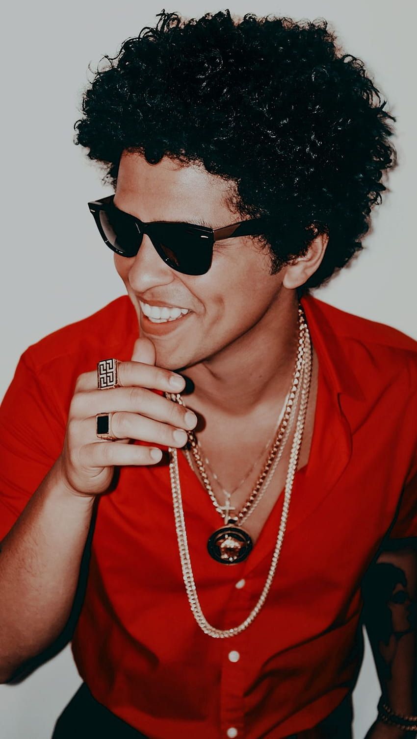 A man wearing sunglasses and holding his phone - Bruno Mars