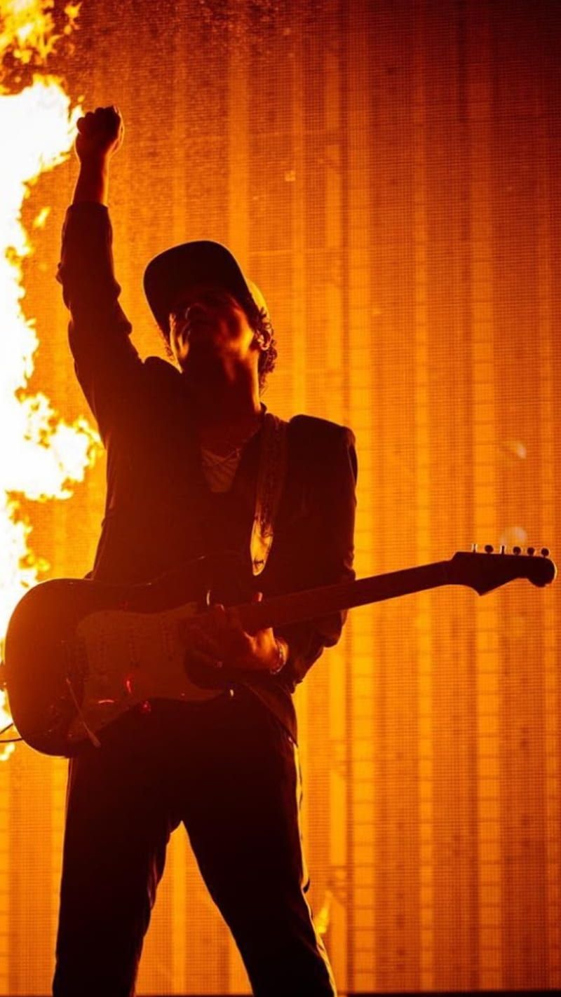 A man playing guitar in front of flames - Bruno Mars