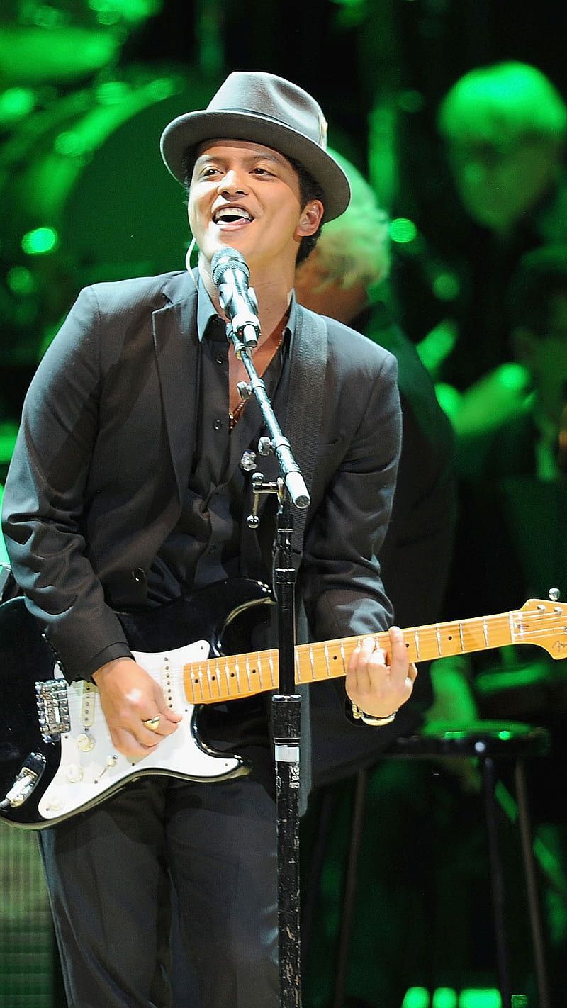 A man in black suit and hat playing guitar - Bruno Mars