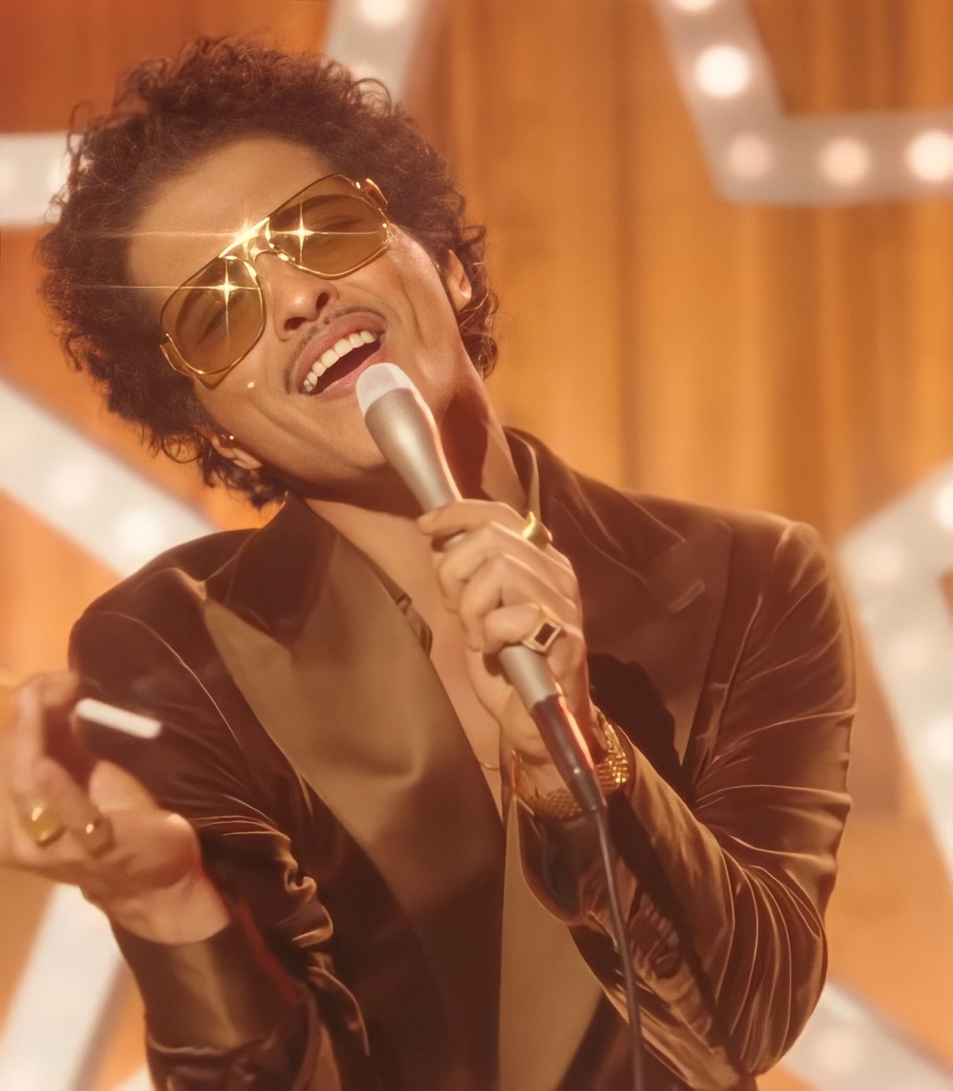 Bruno Mars in a shiny brown suit and sunglasses holding a microphone - Bruno Mars