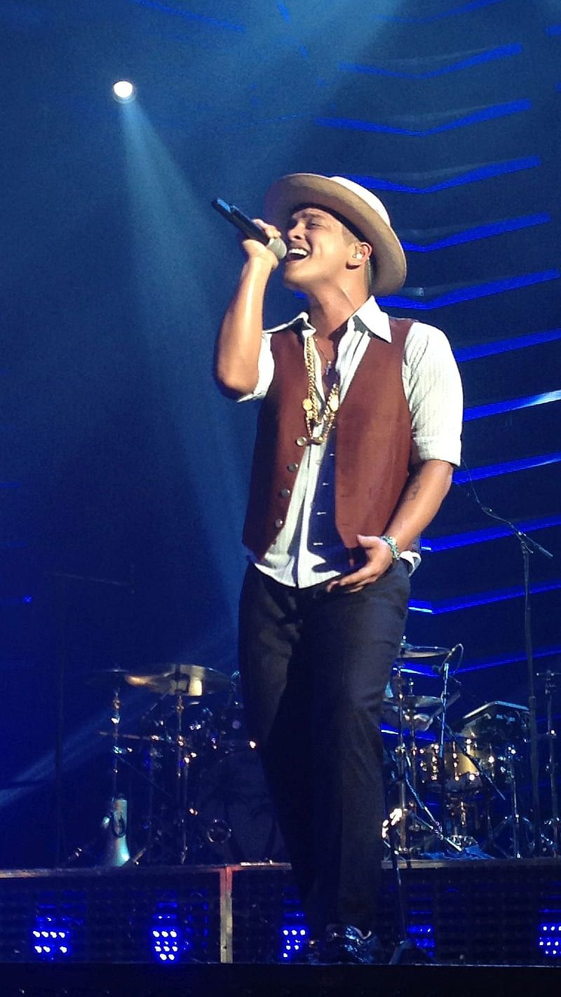 Bruno Mars performs on stage in a brown vest and cowboy hat. - Bruno Mars