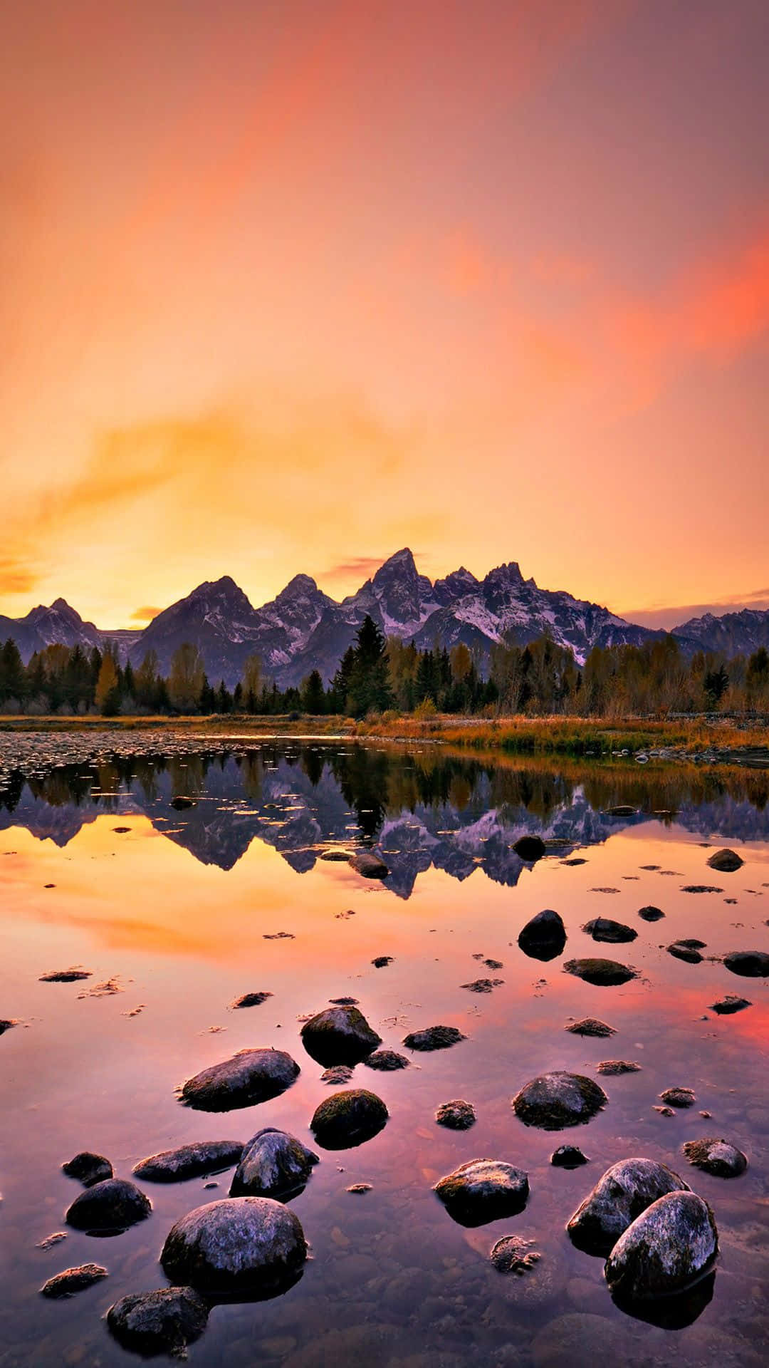 Download Aesthetic Sunset iPhone With Mountains And Forest Reflecting On Lake Wallpaper